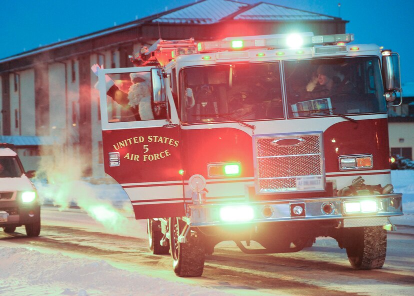 Santa Claus arrives at the tree-lighting ceremony in a fire truck and waves at Team Malmstrom members attending the ceremony. He and the 341st Operations Group commander lit the tree, marking the beginning of the base's winter holiday celebrations.  (U.S. Air Force photo/Senior Airman Cortney Paxton)