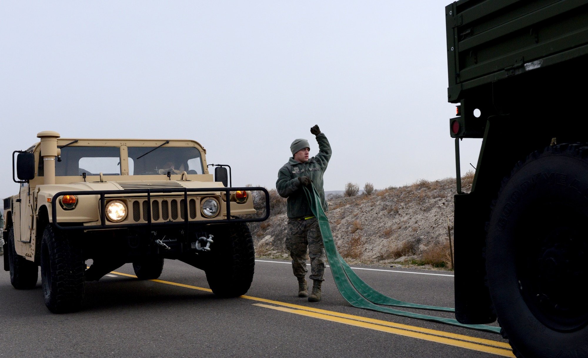 U.S. Air Force Airman 1st Class Ethan Croce, 366th Logistic Readiness Squadron vehicle operator, directs a vehicle into a towing position in order to flat tow a humvee during Convoy Operations Readiness Training, Dec. 6, 2013, near Mountain Home Air Force Base, Idaho. The training prepared vehicle operators for deployment situations, as well as provided them with the skill sets necessary to their military career. (U.S. Air Force photo/Senior Airman Caitlin Guinazu/Released)
