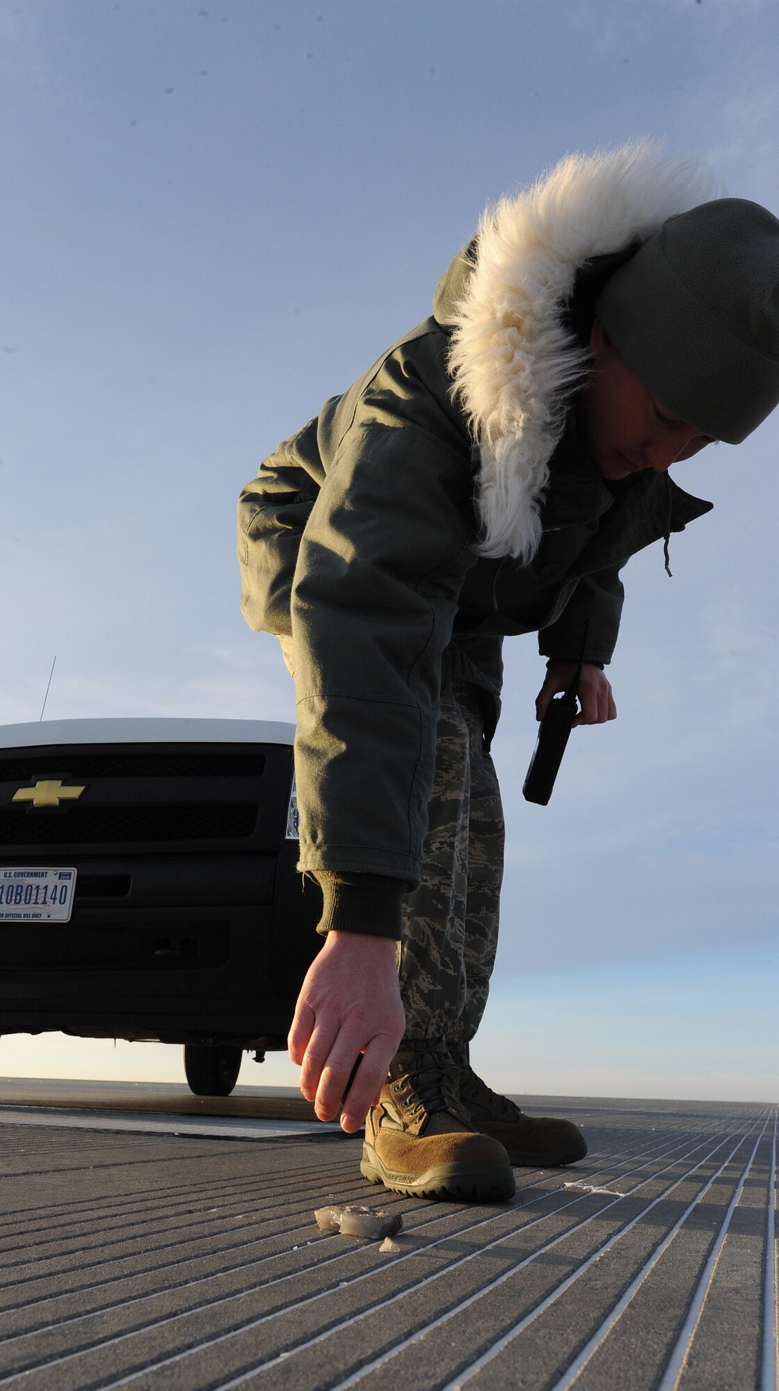 Staff Sgt. Jeffery Heath, 5th Operations Support Squadron Airfield Management, picks up debris on the runway here, Dec. 11, 2013. Heath inspects the runway for foreign object debris routinely throughout the day, making sure the runway is safe for usage. (U.S. Air Force photo/Airman 1st Class Andrew Crawford)