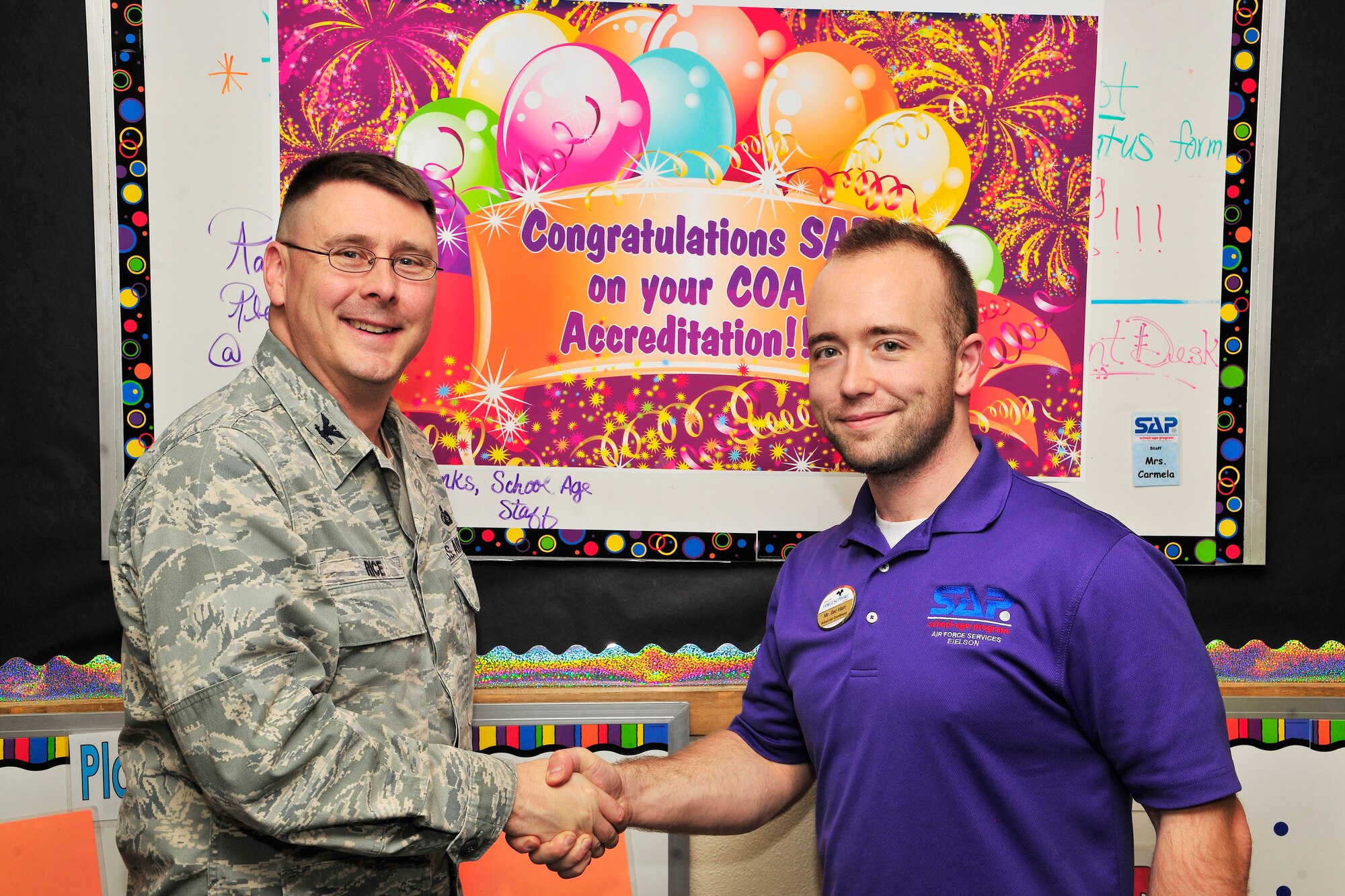 Col. Larry Rice, 354th Mission Support Group commander, congratulates Zachary Hart, 354th Force Support Squadron School Age Program director Nov. 22, 2013, Eielson Air Force Base, Alaska. Eielson’s School Age Program received national accolades and certification from the Council on Accreditation. (U.S. Air Force photo by Staff Sgt. Jim Araos/Released) 