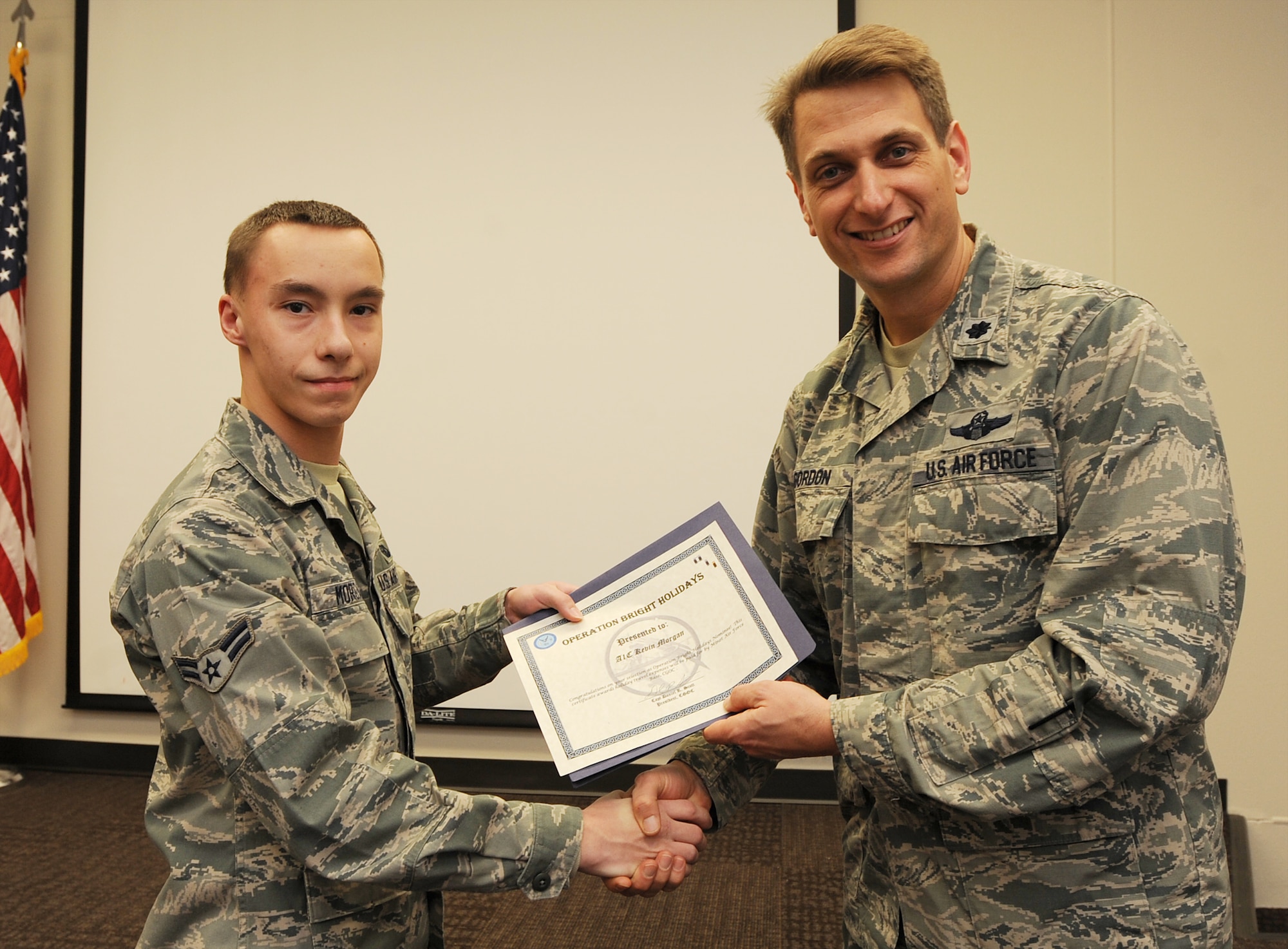Airman 1st Class Kevin Morgan, of the 5th Operations Support Squadron, is presented the Operation Bright Holidays award by Lt. Col. David Gordon, 5th OSS commander, on behalf of the Company Grade Officer’s Council, Dec. 11. As the award recipient, Morgan will be sponsored by the CGOC for a trip home to his family. Operation Bright Holidays is a CGOC-led program that was created to give Airmen in need, an opportunity to go home for the holidays. Donations were requested to local businesses, and the CGOC was able to raise $3,071 to send five Airmen home for the holidays. (U.S. Air Force photo/Senior Airman Jose L. Hernandez-Domitilo)