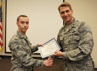 Airman 1st Class Kevin Morgan, of the 5th Operations Support Squadron, is presented the Operation Bright Holidays award by Lt. Col. David Gordon, 5th OSS commander, on behalf of the Company Grade Officer’s Council, Dec. 11. As the award recipient, Morgan will be sponsored by the CGOC for a trip home to his family. Operation Bright Holidays is a CGOC-led program that was created to give Airmen in need, an opportunity to go home for the holidays. Donations were requested to local businesses, and the CGOC was able to raise $3,071 to send five Airmen home for the holidays. (U.S. Air Force photo/Senior Airman Jose L. Hernandez-Domitilo)