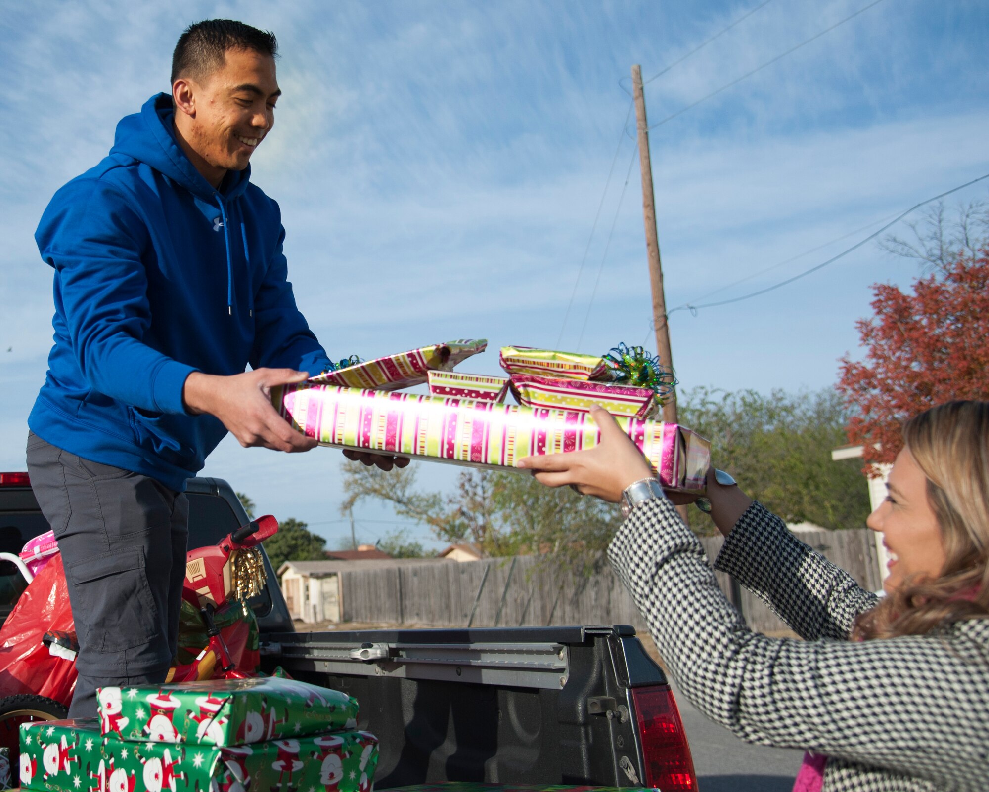 Second Lt. Nico Gigante, left, 47th Student Squadron student pilot, hands gifts to Yanet Darden, right, Pathways family specialist, to help unload his truck on Dec. 11, 2013. Gigante had the 47th STUS help donate gifts to help the local children group home. (U.S. Air Force photo/2nd Lt. William M. Tyrrell)