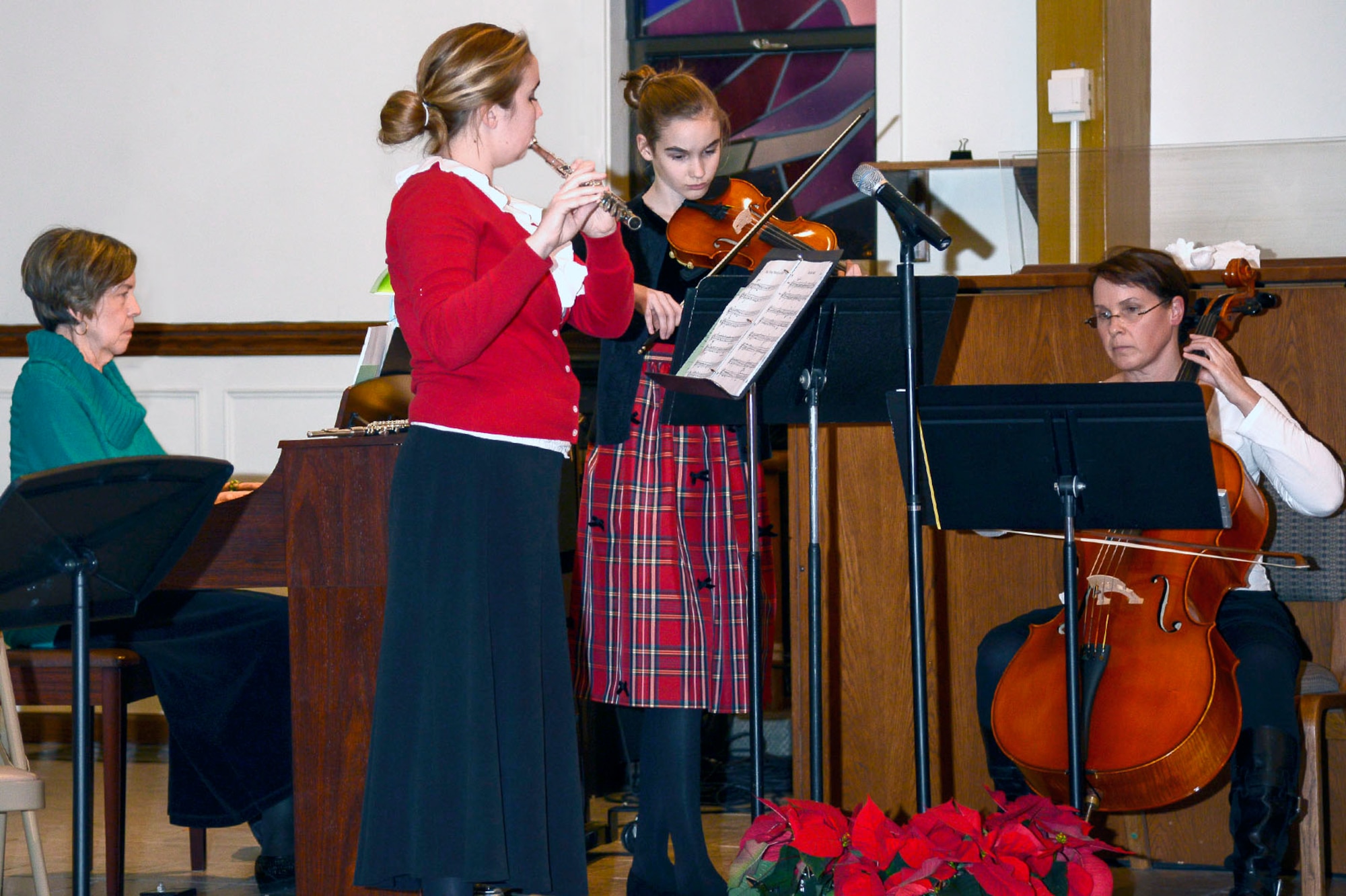 Ann Meffan (left to right) Emma and Ellie Ferguson, playing the flute and violin respectively, as well as Paige Ferguson perform during the Christmas Tree Lighting ceremony Dec. 4 at the base chapel. The event began with Christmas music inside the sanctuary, was followed by flipping the switch outside to light the tree and ended with the arrival of Santa Claus on a fire truck. (U.S. Air Force photo by Walter Santos)