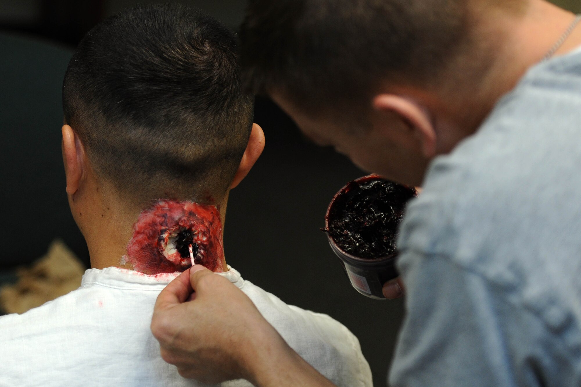 ALTUS AIR FORCE BASE Okla. – U.S. Air Force Master Sgt. Travis Parker, 97th Medical Support Squadron resource management flight chief, applies moulage on U.S. Air Force Master Sgt. Erick Epstein, 97th MDSS medical logistics flight chief, as part of an active-shooter exercise Dec. 11, 2013. Epstein played the role of the assailant for the active-shooter scenario. Bases across the Department of Defense train for events like these to prevent unnecessary loss of life.  (U.S. Air Force photo by Airman 1st Class Klynne Pearl Serrano/Released)