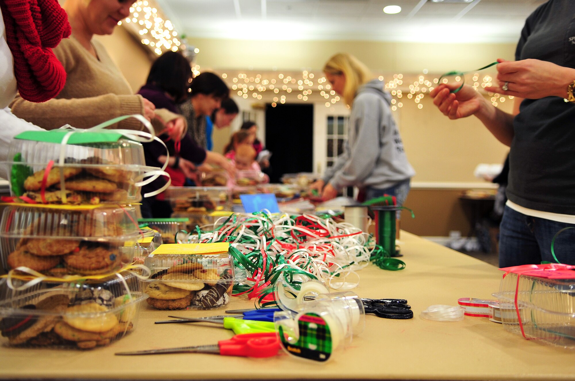 Members of Team Seymour wrap cookie-filled containers with ribbons and Christmas cards at the Spitfire Pub at Seymour Johnson Air Force Base, Dec. 10, 2013. Members of The Officer and Civilian Spouses’ Club, a private organization which helps military spouses get involved with the base community, collected cookies for the annual Airman Cookie Drive to distribute to Airman living in the dorms during the holidays. (U.S. Air Force photo by Airman 1st Class Shawna Keyes)