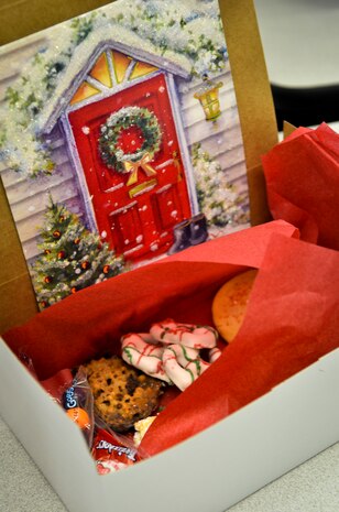 Cards written by local school children to deployed members of Joint Base Charleston are added to the cookie boxes before being wrapped with bows and shipped overseas Dec.11, 2013, at the Chapel Annex on Joint Base Charleston — Air Base, S.C. The Team Charleston Spouses Club collected more than 6,500 cookies and edible goods to be distributed to deployed members Joint Base Charleston, the Gaylor Dining Facility and the Naval Weapon Station Galley. (U.S. Air Force photo/Airman 1st Class Michael Reeves)