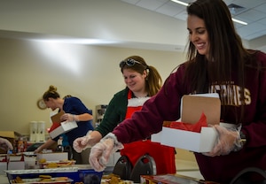 Kristen Neukom (center), Team Charleston Spouses Club vice president and Kaitlyn Litton (right), assemble boxes of cookies as part of Operation: Cookie Drop, Dec. 11, 2013, at the Air Base Chapel Annex on Joint Base Charleston — Air Base, S.C. The Team Charleston Spouses Club collected more than 6,500 cookies and edible goodies to be distributed to deployed members of Joint Base Charleston, the Gaylor Dining Facility and the Naval Weapons Station Galley. (U.S. Air Force photo/Airman 1st Class Michael Reeves)