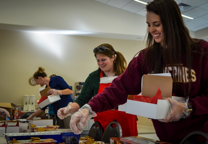 Kristen Neukom (center), Team Charleston Spouses Club vice president and Kaitlyn Litton (right), assemble boxes of cookies as part of Operation: Cookie Drop, Dec. 11, 2013, at the Air Base Chapel Annex on Joint Base Charleston — Air Base, S.C. The Team Charleston Spouses Club collected more than 6,500 cookies and edible goodies to be distributed to deployed members of Joint Base Charleston, the Gaylor Dining Facility and the Naval Weapons Station Galley. (U.S. Air Force photo/Airman 1st Class Michael Reeves)