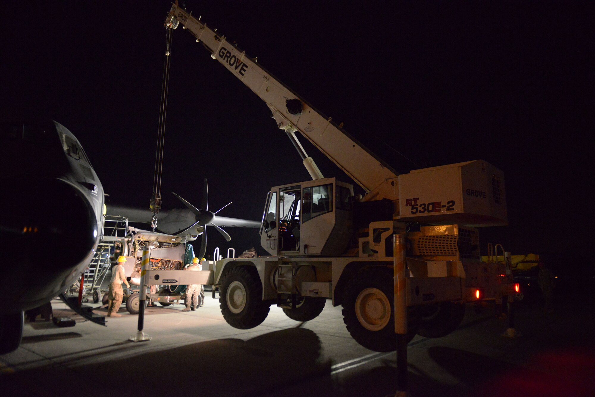 Airmen from the 379th Expeditionary Aircraft Maintenance Squadron, 746th Expeditionary Aircraft Maintenance Unit propulsion flight and 557th Expeditionary Red Horse Squadron heavy equipment operators, fasten an engine on to an engine stand during an engine swap at the 379th Air Expeditionary Wing, Southwest Asia, Dec. 11, 2013. The engine was swapped out in 12 hours and the aircraft was ready to fly on schedule. (U.S. Air Force photo/Master Sgt. David Miller)