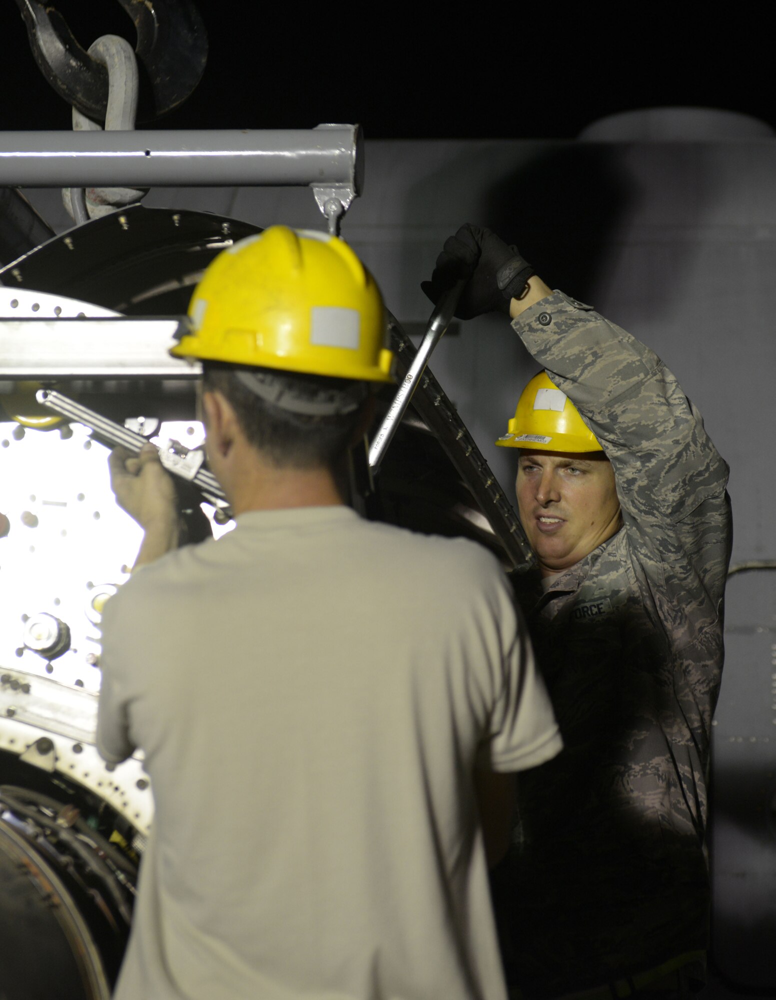 Tech. Sgt. Russell O’Farrell (background) and Senior Airman Michael Johnson (foreground), 379th Expeditionary Aircraft Maintenance Squadron, 746th Expeditionary Aircraft Maintenance Unit,align a C-130 fasten an engine on to an engine stand 379th Air Expeditionary Wing, Southwest Asia, Dec. 11, 2013. The 557th Expeditionary Red Horse Squadron provided short notice support for the engine swap by providing the crane and personnel to hoist the engine out and install the new engine. The combined efforts contributed to the engine being changed out in 12 hours and the aircraft ready to fly on schedule. O’Farrell is a propulsion craftsman deployed from Keesler Air Force Base, Miss., and a Pensacola, Fla., native. Johnson is a propulsion journeyman deployed from Keesler Air Force Base, Miss., and a Mobile, Ala., native. (U.S. Air Force photo/Master Sgt. David Miller)