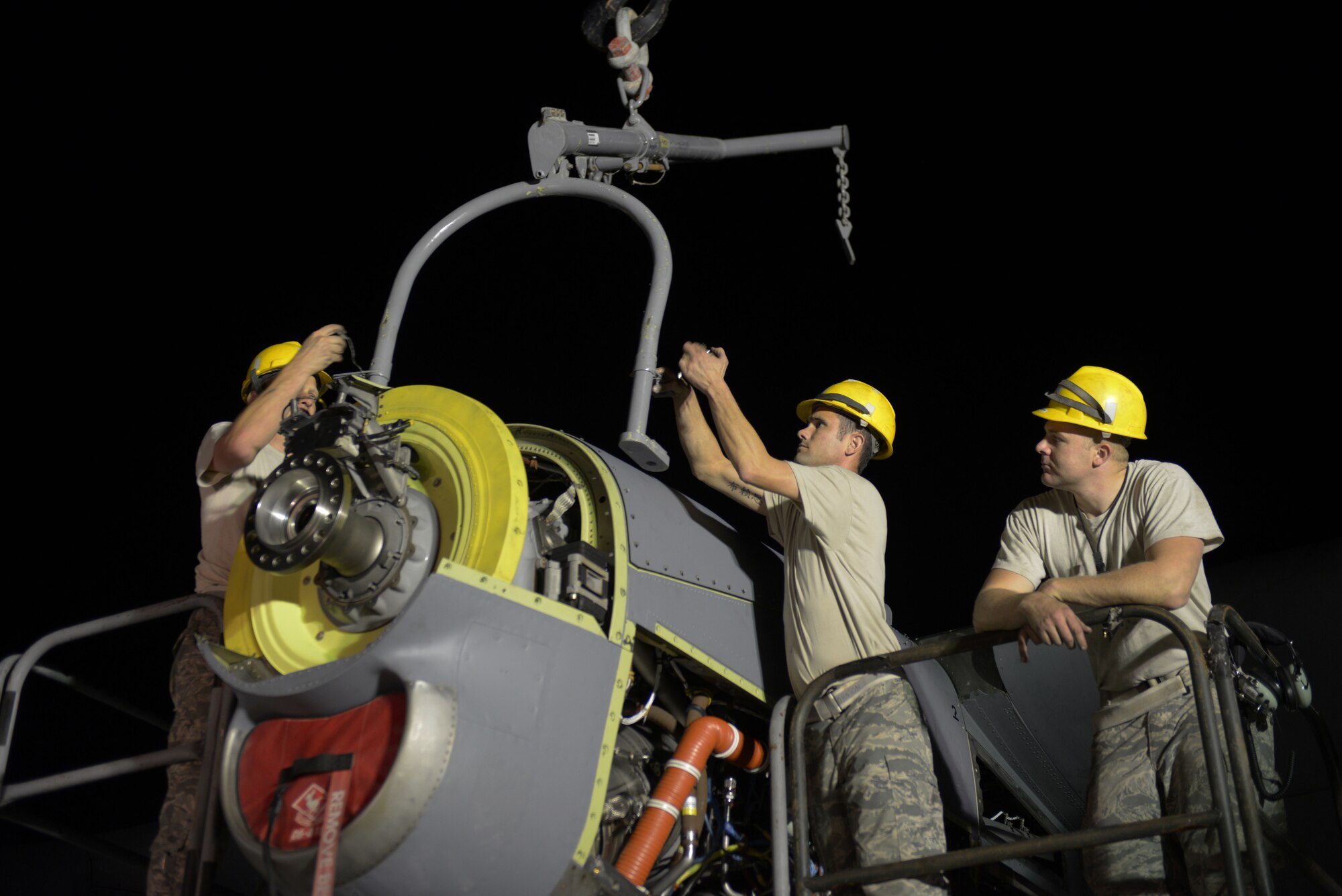Airmen from the 379th Expeditionary Aircraft Maintenance Squadron, 746th Expeditionary Aircraft Maintenance Unit propulsion flight, install an engine into a C-130J at the 379th Air Expeditionary Wing, Southwest Asia, Dec. 11, 2013. The 557th Expeditionary Red Horse Squadron provided short notice support for the engine swap by supplying the crane and personnel to hoist the engine out and install the new engine.  The combined efforts contributed to the engine being swapped in 12 hours and the aircraft ready to fly on schedule. (U.S. Air Force photo/Master Sgt. David Miller)