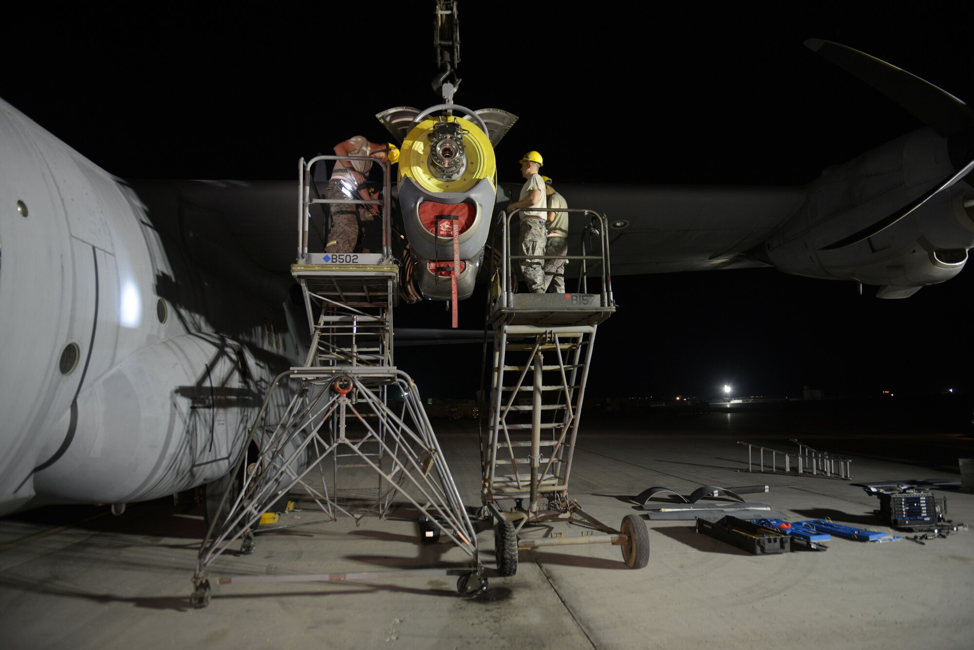 Airmen from the 379th Expeditionary Aircraft Maintenance Squadron, 746th Expeditionary Aircraft Maintenance Unit propulsion flight, install an engine into a C-130J at the 379th Air Expeditionary Wing, Southwest Asia, Dec. 11, 2013. The 557th Expeditionary Red Horse Squadron supported the engine swap by providing the crane and personnel to hoist the engine out and install the new engine. The combined efforts contributed to the engine being swapped in 12 hours and the aircraft ready to fly on schedule. (U.S. Air Force photo/Master Sgt. David Miller)