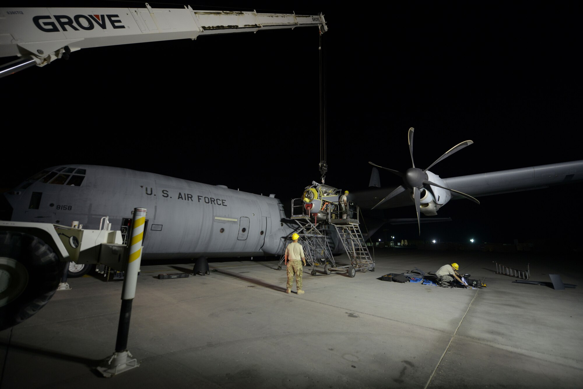 Airmen from the 379th Expeditionary Aircraft Maintenance Squadron, 746th Expeditionary Aircraft Maintenance Unit propulsion flight, install an engine into a C-130J at the 379th Air Expeditionary Wing, Southwest Asia, Dec. 11, 2013. The 557th Expeditionary Red Horse Squadron supported the engine swap by providing the crane and personnel to hoist the engine out and install the new engine. The combined efforts contributed to the engine being swapped in 12 hours and the aircraft ready to fly on schedule. (U.S. Air Force photo/Master Sgt. David Miller)