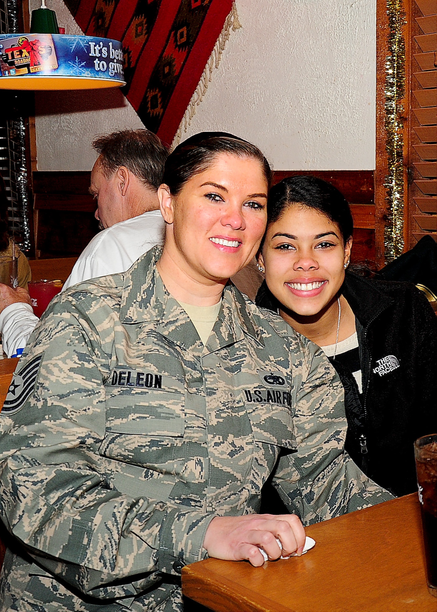 Tech. Sgt. Sabrina Deleon, 436th Maintenance Squadron aerospace ground equipment craftsman, poses with her daughter, Ali Dollins, Dec. 10, 2013, at Texas Roadhouse in Dover, Del. Deleon surprised Dollins at the restaurant after she returned home from a seven-month deployment in an undisclosed location in Southwest Asia. (U.S. Air Force photo/Airman 1st Class Ashlin Federick) 