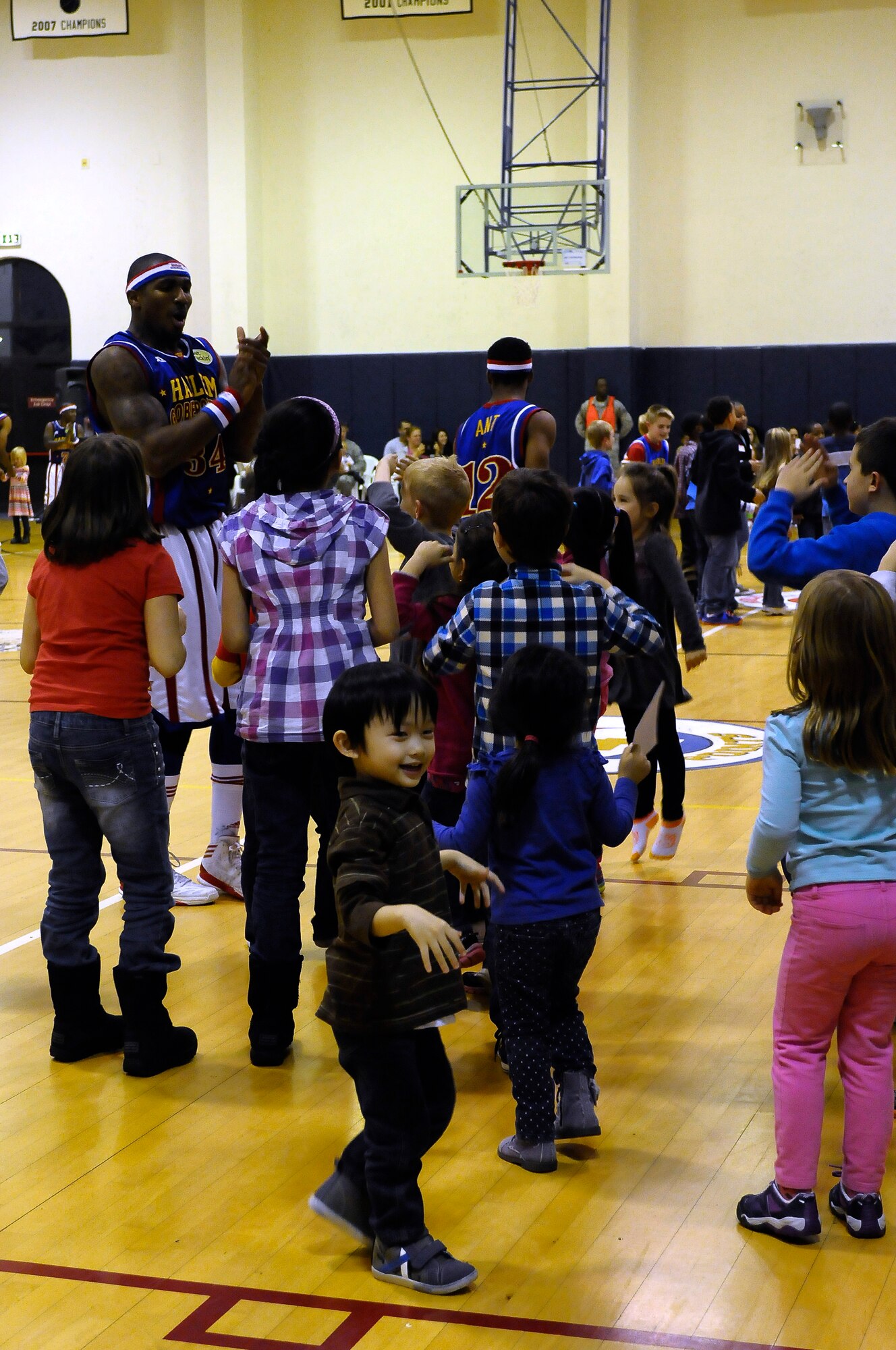 Thunder, Harlem Globetrotters forward, dances with children from the audience during the 12th Annual Harlem Globetrotters Holiday Tour Dec. 10, 2013, at Aviano Air Base, Italy. Throughout the show team members would stop the show to invite audience members to the court for dance-offs, musical chairs or just to say “hi” to service members and their families. (U.S. Air Force photo/Airman 1st Class Deana Heitzman)