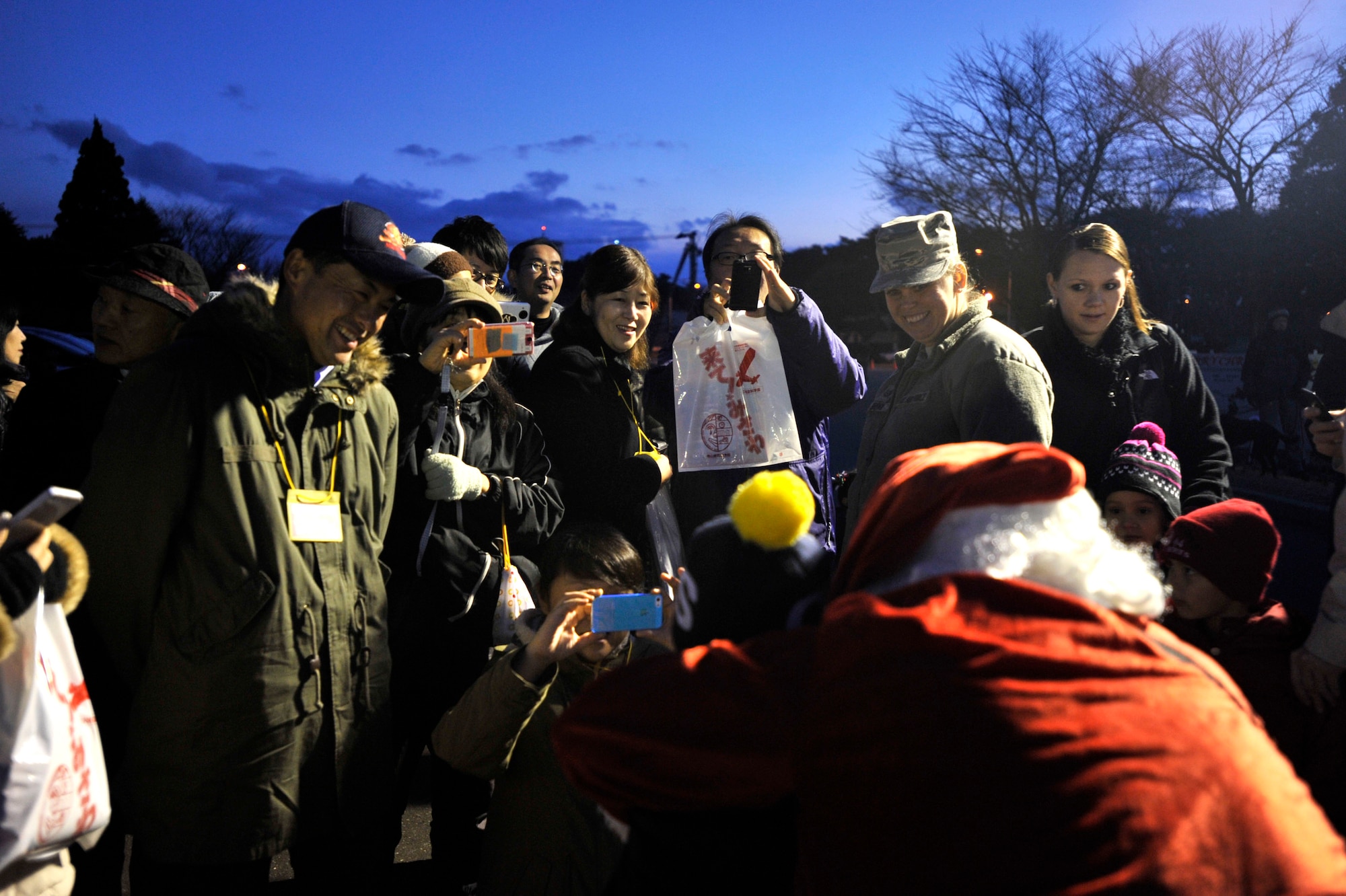 MISAWA AIR BASE, Japan – Santa Clause takes a photo with Airmen and members of the local community during a community relations tour on Misawa Air Base, Dec. 6. The tour was held in conjunction with the annual tree lighting ceremony on Risner Circle. (U.S. Air Force photo by Staff Sgt. Tong Duong)
