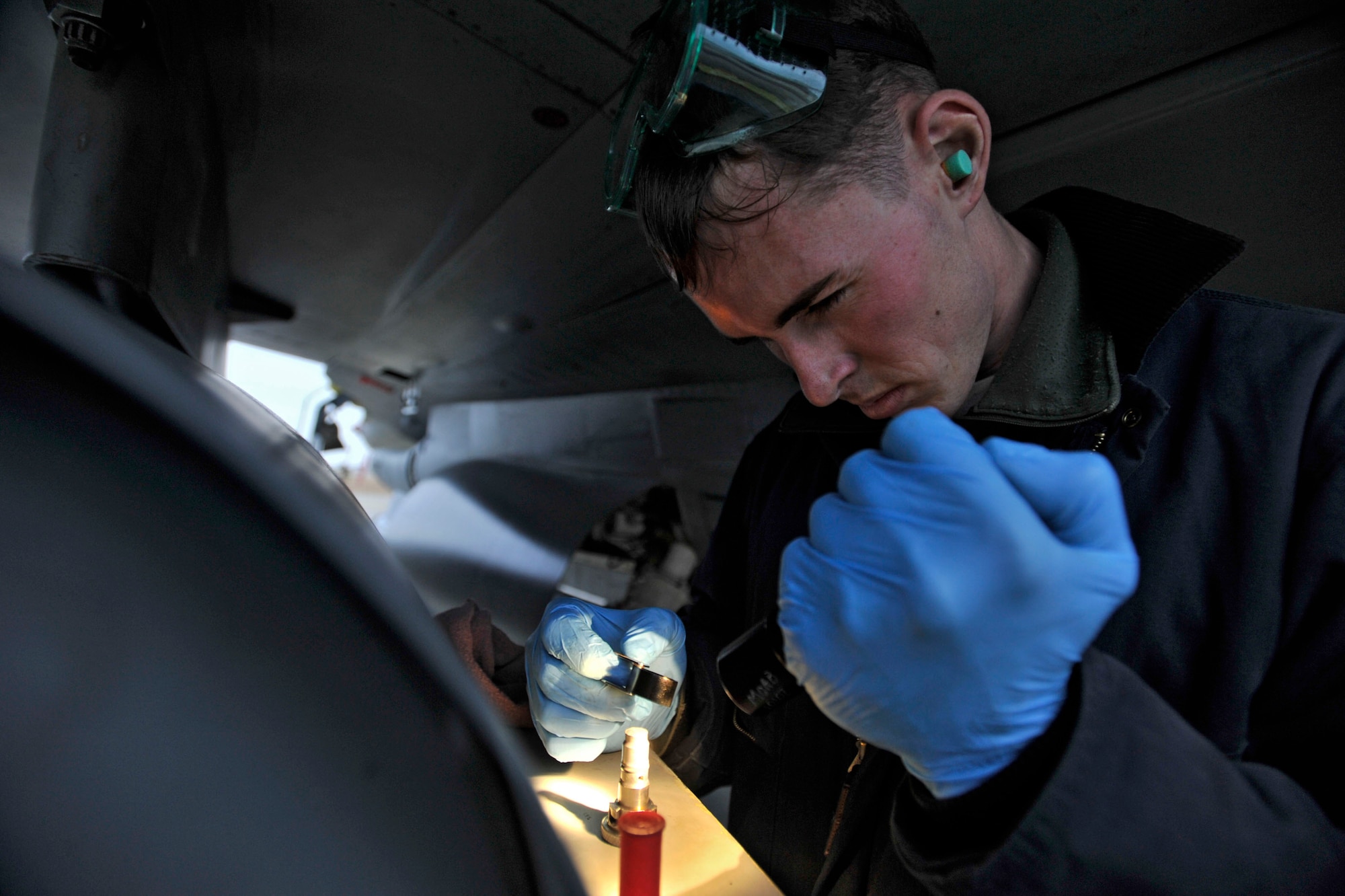 MISAWA AIR BASE, Japan – U.S. Air Force Staff Sgt. Thomas Larson, 14th Aircraft Maintenance Unit crew chief, illuminates a magnetic chip detector while inspecting his assigned F-16 Fighting Falcon at Misawa Air Base, Japan, Dec. 10, 2013. The MCD detects traces of metal particles in the oil system of the aircraft, which helps Larson to determine if the jet is performing at its peak capability. (U.S. Air Force photo by Staff Sgt. Tong Duong)