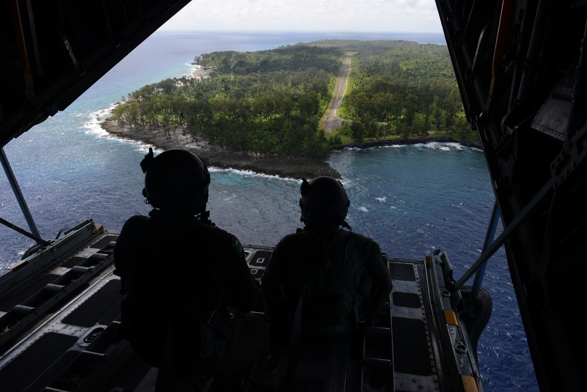 Distinguished visitors and members of the 36th Airlift Squadron, Yokota Air Base, Japan, watch an airdrop bundle land on an isolated island in the Pacific Ocean Dec. 11, 2013, during an Operation Christmas Drop mission. Every December, C-130 Hercules aircrews from the 374th Airlift Wing at Yokota AB partner with the 36th Wing at Andersen Air Force Base, Guam, to airlift food, supplies and toys to islanders throughout Micronesia. (U.S. Air Force photo by Airman 1st Class Emily A. Bradley/Released)