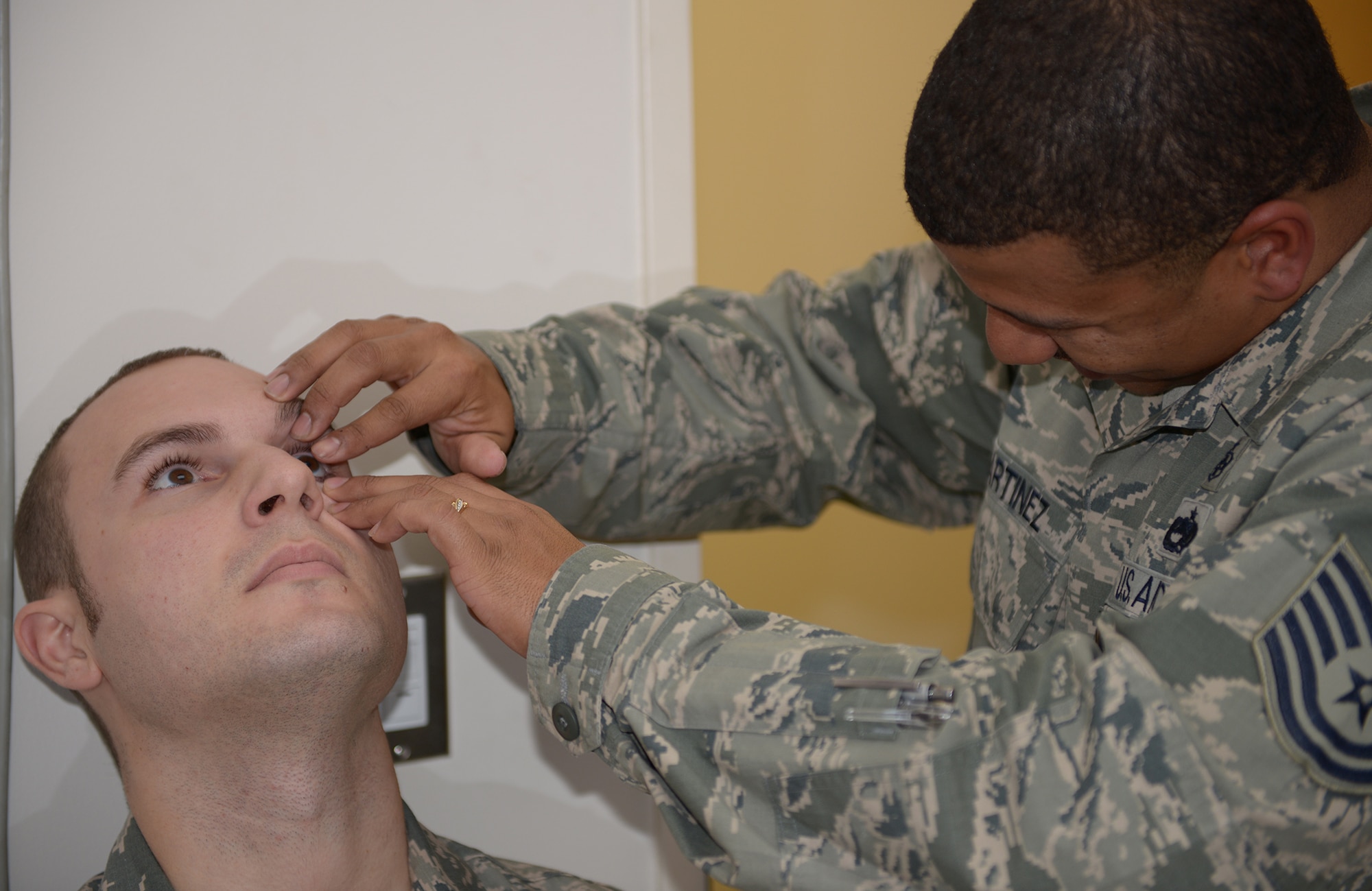 Tech. Sgt. Martinez, 374th Aerospace Medicine Squadron flight chief, removes a contact lens from the eye of Tech. Sgt. David Schnabel, 730th Air Mobility Squadron communication navigation maintainer, at Yokota Air Base, Japan, Dec. 11, 2013. Contact lenses should be replaced according to the manufacturer’s direction to prevent eye infections. (U.S. Air Force photo by Airman 1st Class David Danford/Released)