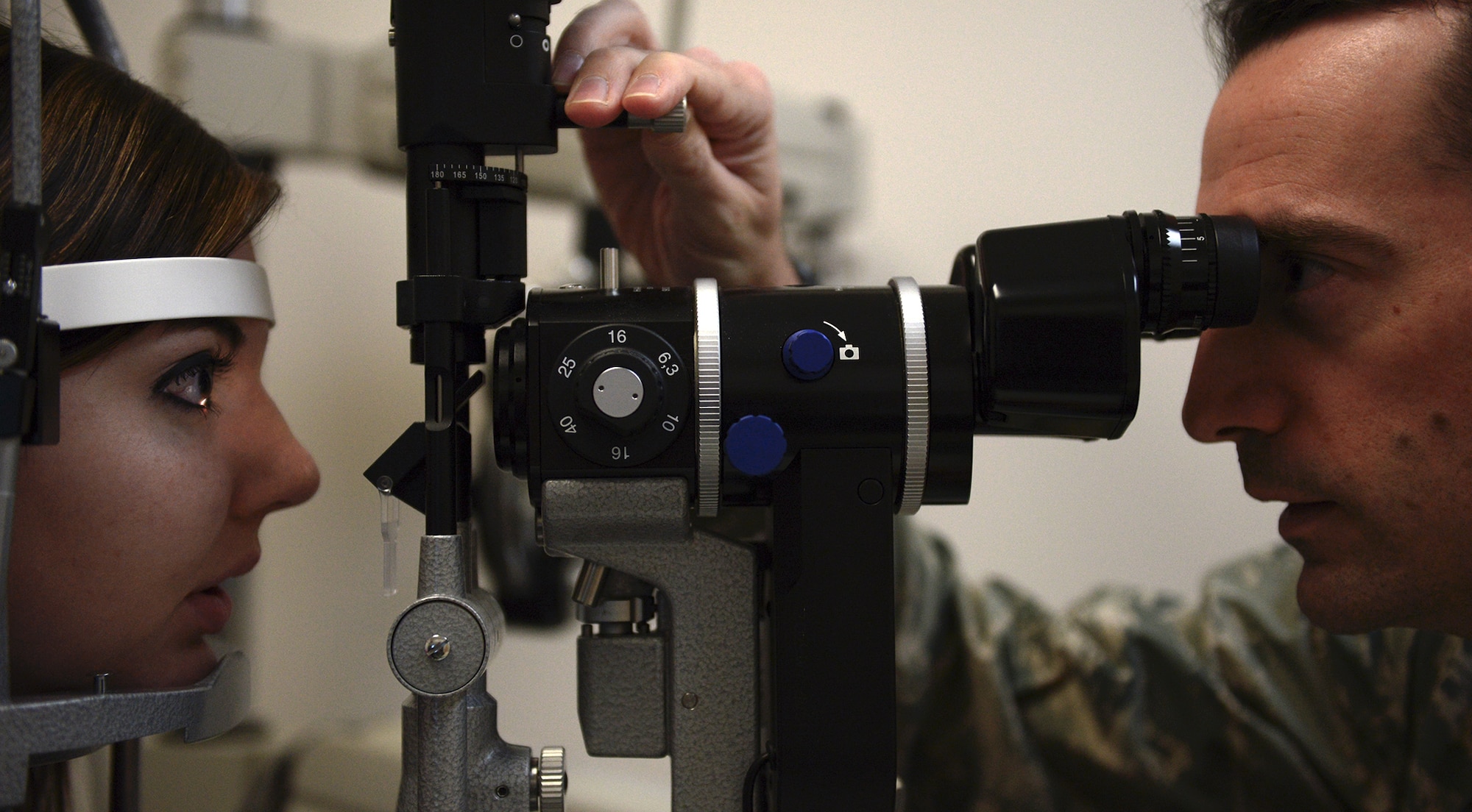 Capt. Benjamin Kolle, 374th Aerospace Medicine Squadron staff optometrist, looks through a microscope into the eyes of Shannon Kline at Yokota Air Base, Japan, Dec. 11, 2013. Kolle has been an Air Force optometrist for 16 months and stationed at Yokota for one year. (U.S. Air Force photo by Airman 1st Class David Danford/Released)