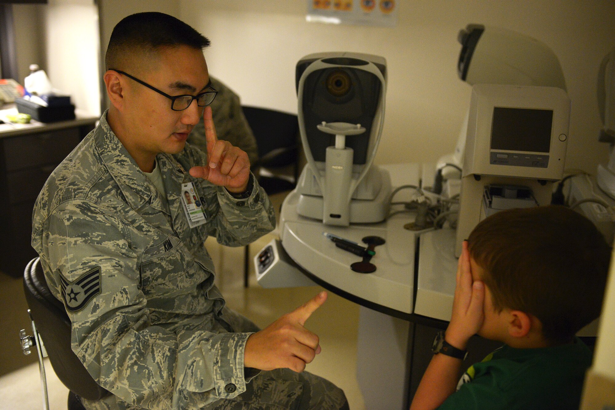 Staff Sgt. Jonghwan Kim, 374th Aerospace Medicine Squadron non-commissioned officer in charge, gives William Baker, son of Capt. Ryan Baker, a focusing test at Yokota Air Base, Japan, Dec. 11, 2013. This was William’s first visit to an optometrist. (U.S. Air Force photo by Airman 1st Class David Danford/Released)