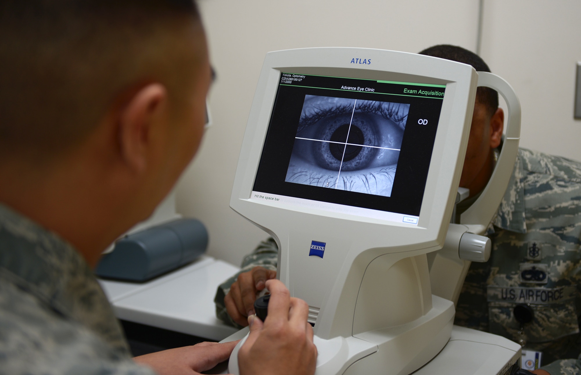 Staff Sgt. Jonghwan Kim and Tech. Sgt. Cristian Martinez, 374th Aerospace Medicine Squadron, display the capabilities of the ATLAS topographer at Yokota Air Base, Japan, Dec. 11, 2013. Corneal topography is a non-invasive medical imaging technique for mapping the surface curvature of the cornea, the outer structure of the eye, which determines vision quality. (U.S. Air Force photo by Airman 1st Class David Danford/Released)