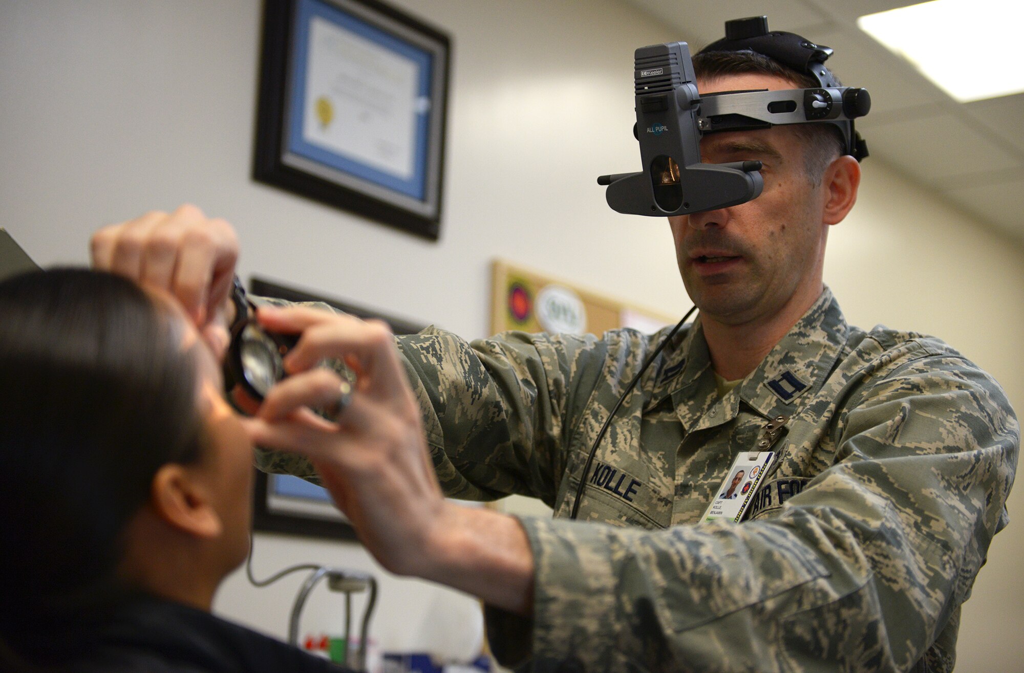 Capt. Benjamin Kolle, 374th Aerospace Medicine Squadron staff optometrist, views Tech. Sgt. Khrysallis Santos’s eye through a magnifying lens at Yokota Air Base, Japan, Dec. 11, 2013. After dilating the pupil, Kolle is able to see irregularities within the eye. (U.S. Air Force photo by Airman 1st Class David Danford/Released)