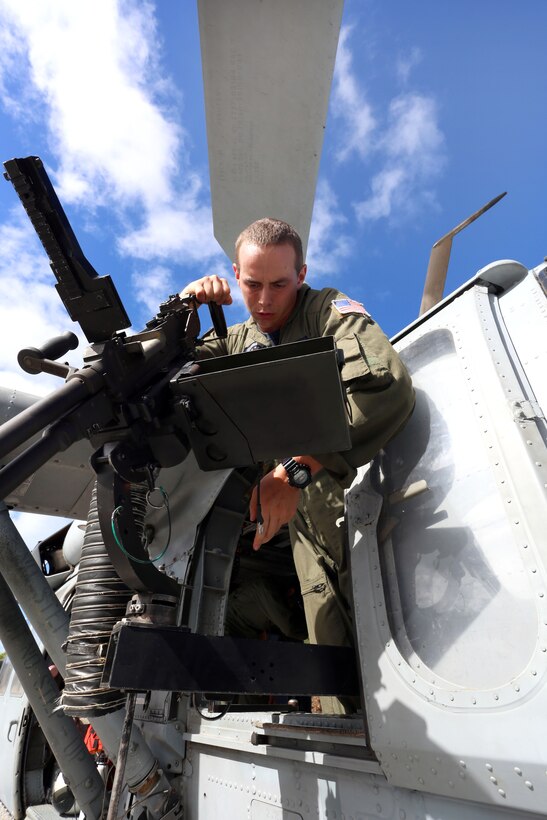 U.S. Navy Petty Officer Petty Officer 2nd Class Conrad P. Hass checks a M240 machine gun mounted in a MH-60S Seahawk helicopter before executing live-fire, close-air support training at Farallon de Medinilla Target Range, Northern Mariana Islands, Dec. 10, 2013.