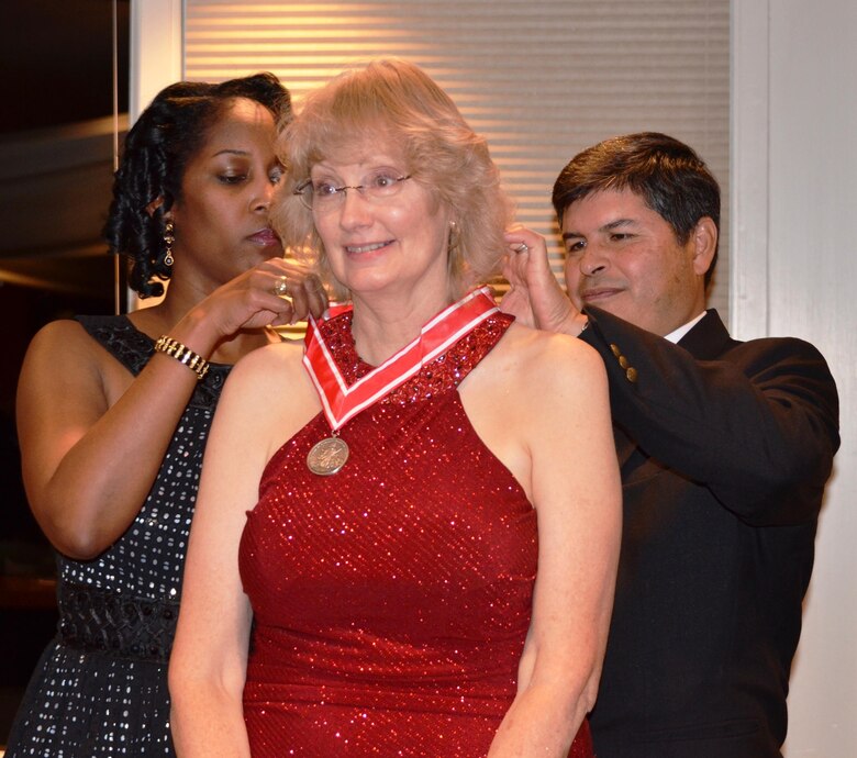 ALBUQUERQUE, N.M., -- Lt. Col. Antoinette Gant and Chief of Engineering and Construction John Moreno present Engineering Technician Joan Roll with the Steel de Fleury Medal for "superior service to the Engineer Regiment as it supports the Army," Dec. 6, 2013. 