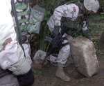 A member of 1st Brigade Combat Team lifts a Styrofoam lid covering the hole where former Iraqi dictator Saddam Hussein was discovered hiding Dec.13 in the village of Ad Dawr. Photo by Staff Sgt. David Bennett, USA 
