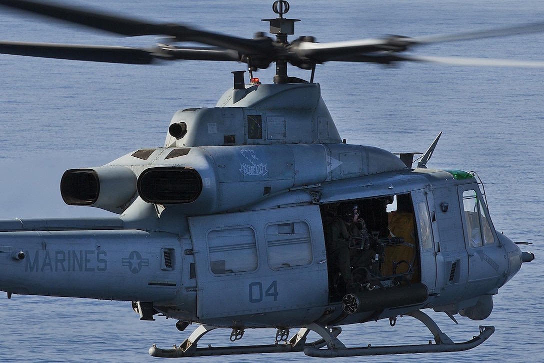 A Marine with Marine Light Attack Helicopter Squadron 367 looks out at the ocean from a UH-1Y Huey helicopter during a commemoration flyover of the USS Missouri and the USS Arizona Memorial in Pearl Harbor, Dec. 5, 2013. “Scarface” celebrated its 70th anniversary in the Marine Corps, Dec 1., and flew four AH-1W Super Cobra and UH-1Y Huey helicopters over Pearl Harbor to commemorate its history. (U.S. Marine Corps photo by Lance Cpl. Matthew Bragg)