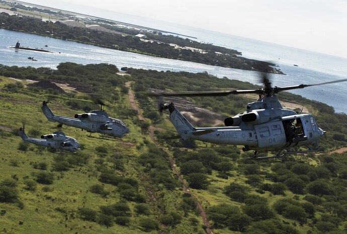 A UH-1Y Huey helicopter and two AH-1W Super Cobra helicopters prepare to fly over the USS Missouri and the USS Arizona Memorial in Pearl Harbor, Hawaii, while sailors conduct maintenance on a submarine in the distance, Dec. 5, 2013. Marine Light Attack Helicopter Squadron 367 celebrated its 70th anniversary in the Marine Corps, Dec. 1., and flew four AH-1W Super Cobra and UH-1Y Huey helicopters over Pearl Harbor to commemorate its history. (U.S. Marine Corps photo by Lance Cpl. Matthew Bragg)