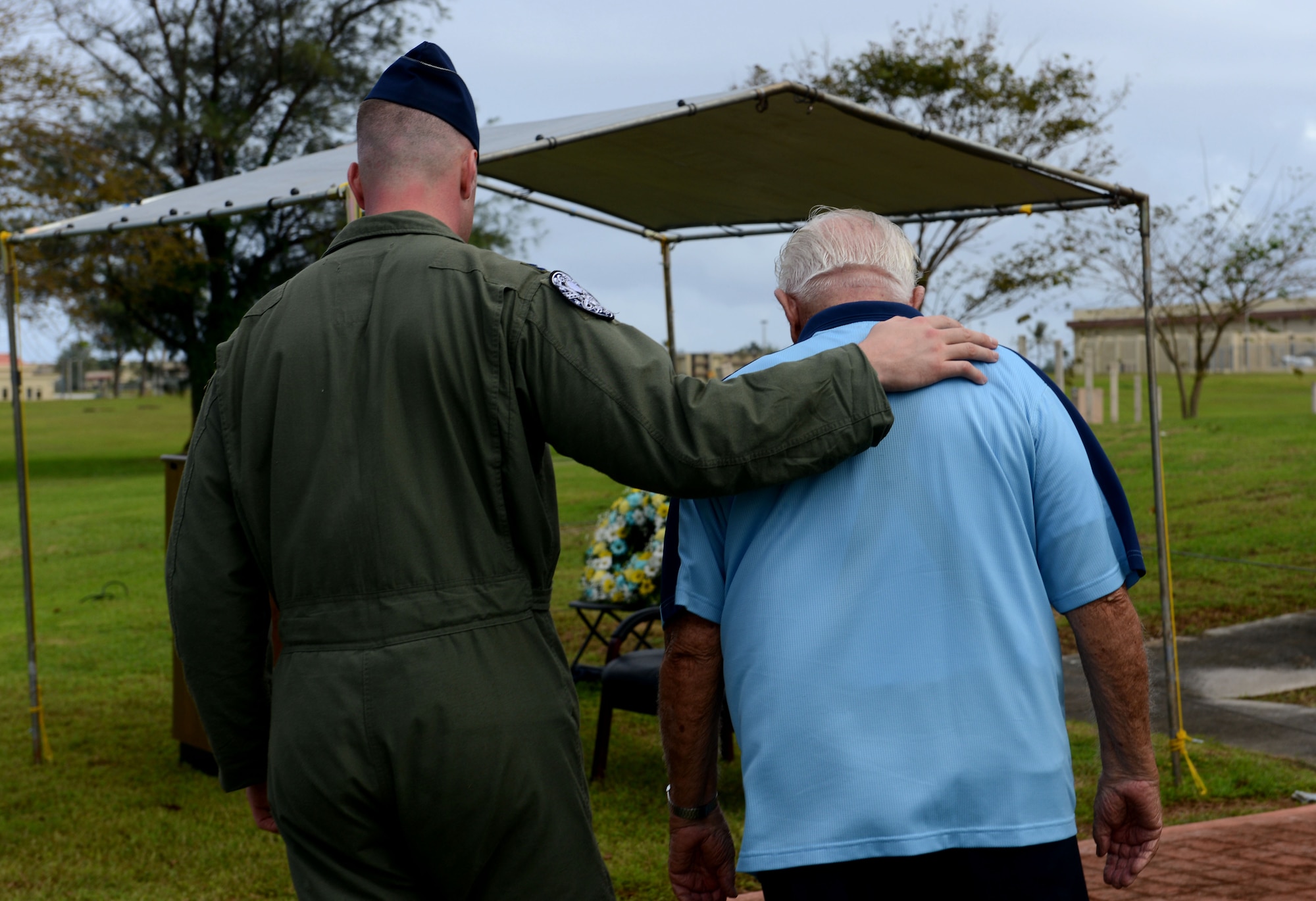 Capt. Andrew Johnson leads retired Lt. Col. Charles "Chuck" McManus to his seat prior to the Linebacker II ceremony Dec. 13, 2013, on Andersen Air Force Base, Guam. McMamus was a B-52 Stratofortess navigator during Operation Linebacker II, which took place in North Vietnam in December 1972. (U.S. Air Force photo by Airman 1st Class Emily A. Bradley/Released)