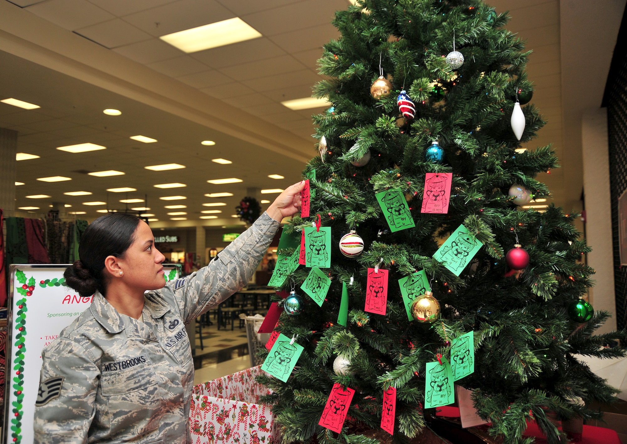 U.S. Air Force Staff Sgt. Gloria Westbrooks 355 Fighter Wing command chief’s executive assistant, selects a donation card from the holiday tree at the Base Exchange at Davis-Monthan Air Force Base, Ariz. Dec. 12, 2013. Service members select cards which contain a desired gift from a local area child and then purchase the gift for donation. (U.S. Air Force photo by Senior Airman Josh Slavin/Released)