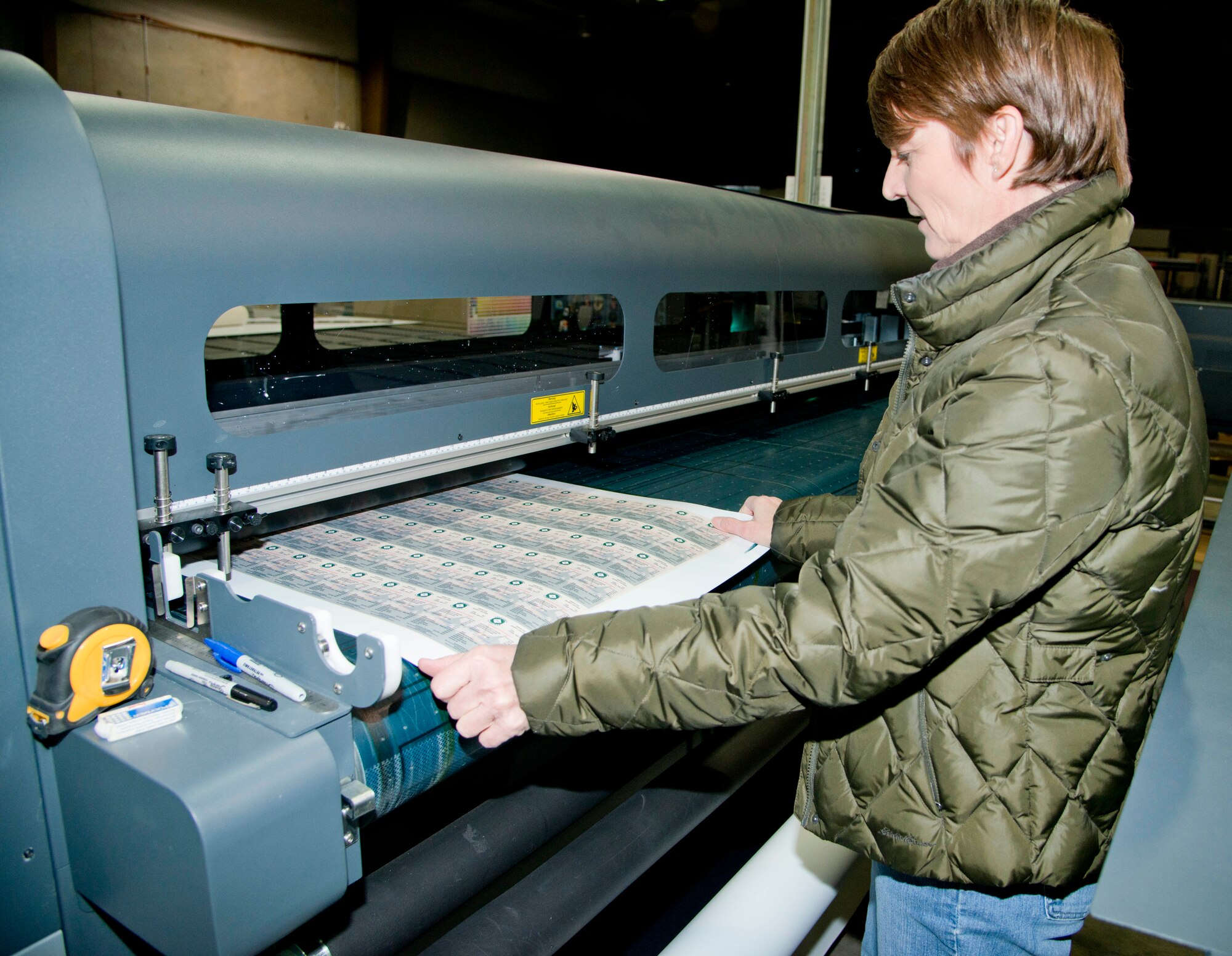 Kathy Kruczek, Defense Logistics Agency Document Services graphics artist, examines a sheet of magnets as the leave the Scitex Flatbed Printer Tuesday. DLA is the Department of Defense's primary source for document automation and printing. (U.S. Air Force photo/Senior Airman Nicole Leidholm)