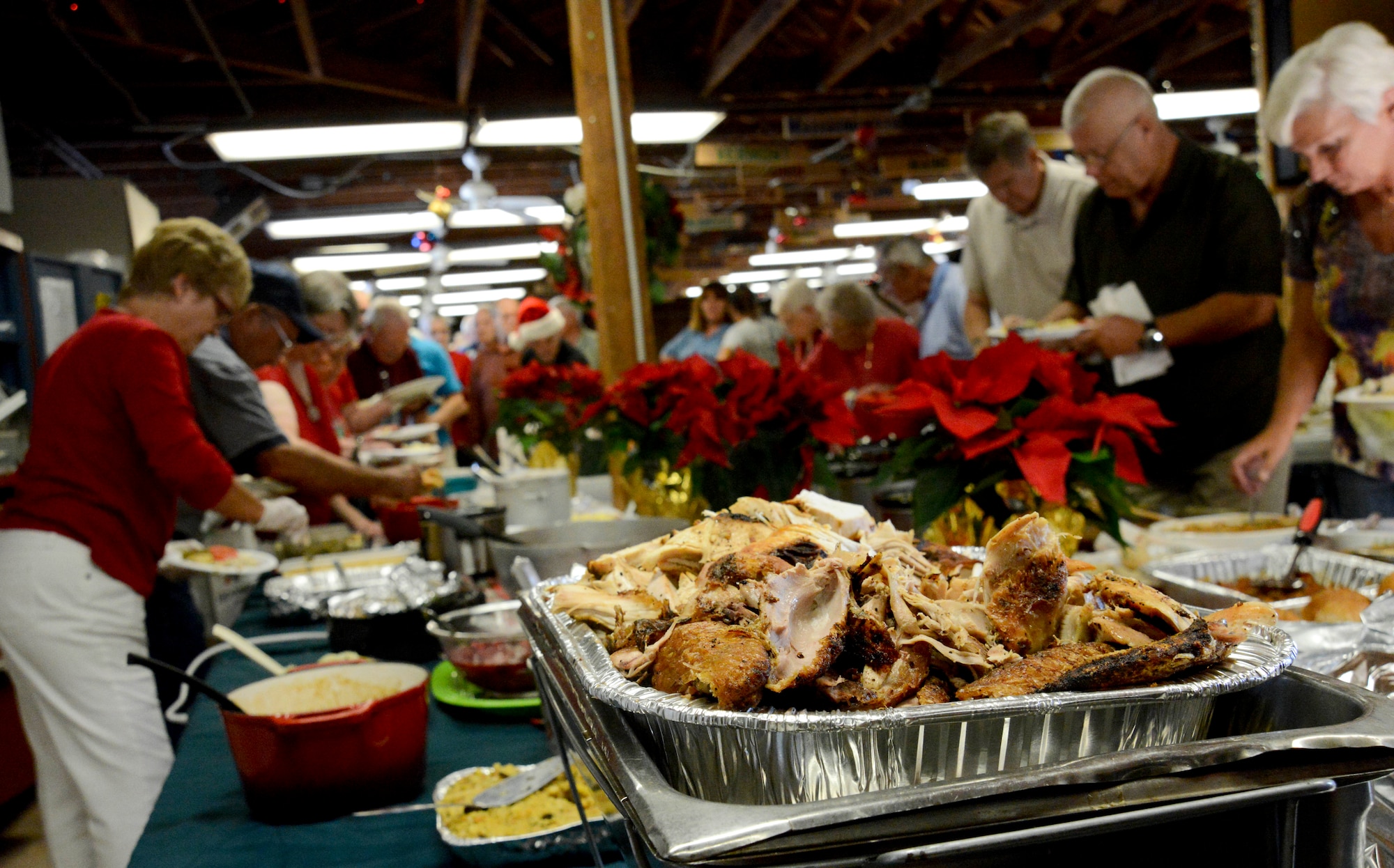 Residents and attendees of the FAMCAMP Welcome Back Party prepares their plates to eat Dec. 13, 2013 at MacDill Air Force Base, Fla. The event consisted of a potluck lunch, live music, sponsorship tables, and holiday decoration prize giveaway along with opening remarks by base leadership.(U.S. Air Force photo by Senior Airman Jenay Randolph/Released)