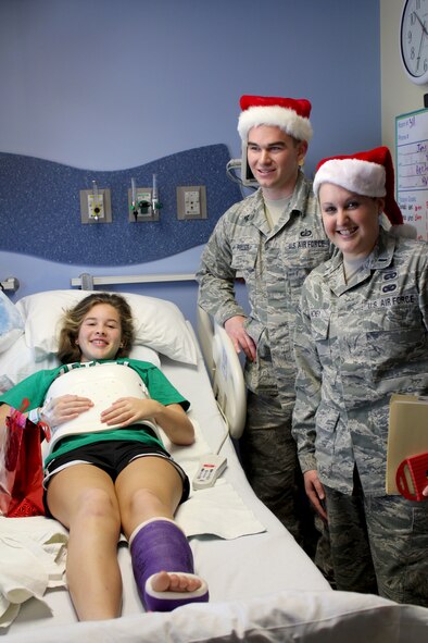 Staff Sgt. Logan Fuller and 1st Lt Jordan Hickey of the 178th Fighter Wing deliver a gift to a patient at Childrens Medical Center, Dayton, Ohio Dec. 12 as part of the wing's Comany Grade Officer's Council organized event. More than 75 gifts were handed out. (U.S. Air Force photo by SSgt. Elisabeth Gelhar, cleared for release)