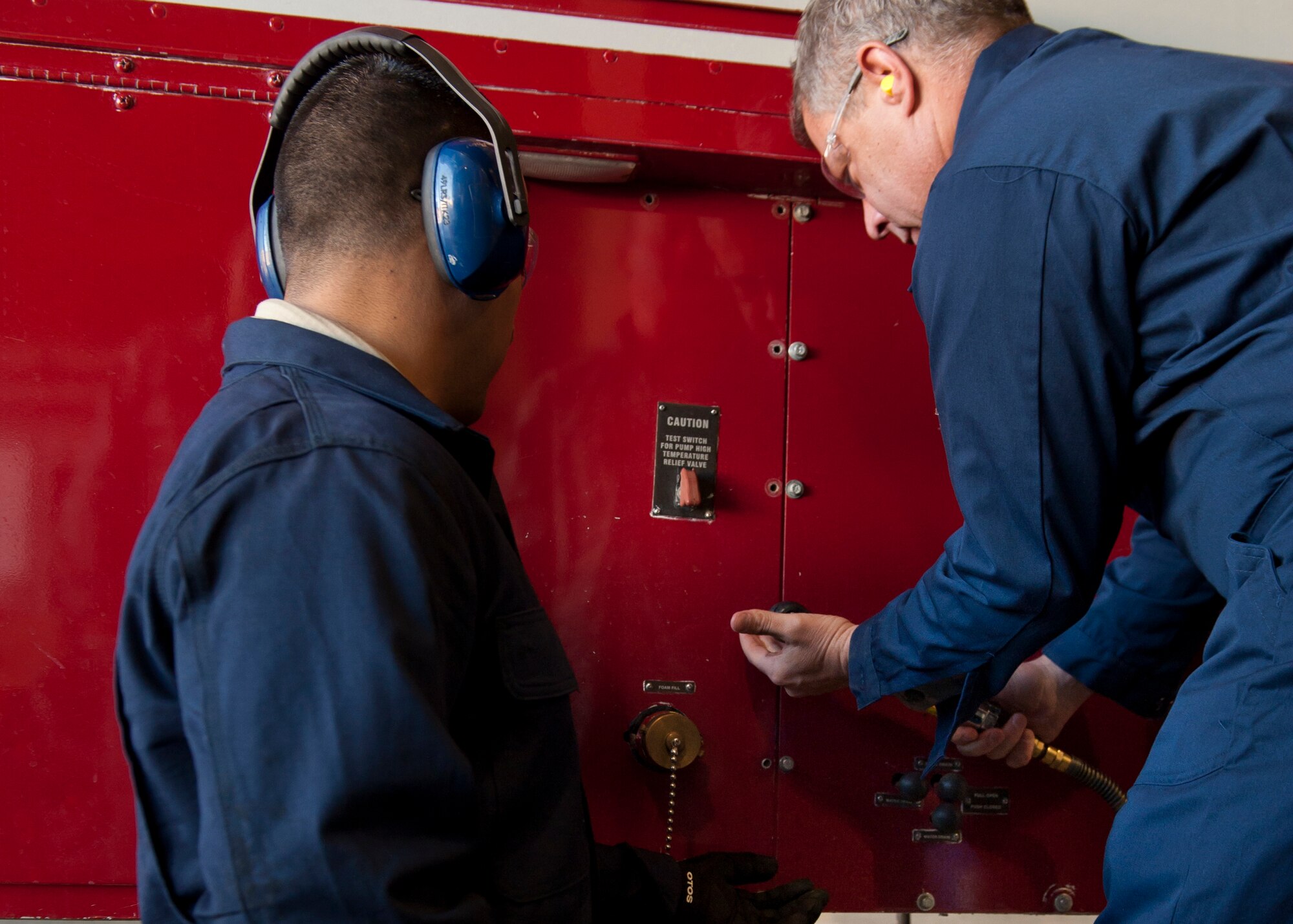 Senior Airman Fabian Garcia, fire truck mechanic instructs Col. Kevin Bennett, 49th Mission Support Group commander on how to remove the side panel of a P-19 fire truck in order to replace a relief valve at Holloman Air Force Base, N.M., Dec. 11. Bennett spent the day working hands-on with fire truck mechanics of the 49th Logistics Readiness Squadron to get an insight of their daily life and connect with the airmen. (U.S. Air Force photo by Airman 1st Class Aaron Montoya/Released)