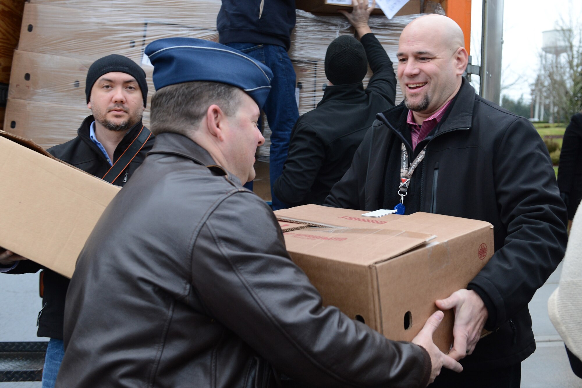 Col. Jeffrey Philippart, 62nd Airlift Wing vice commander, receives a box of hams from Corey Hammond, U.S. Family Health Plan representative, during Operation Ham Grenade Dec. 13, at Joint Base Lewis-McChord, Wash. Hams were donated by local community members from Pierce County and local chambers. (U.S. Air Force photo/Airman 1st Class Jacob Jimenez)