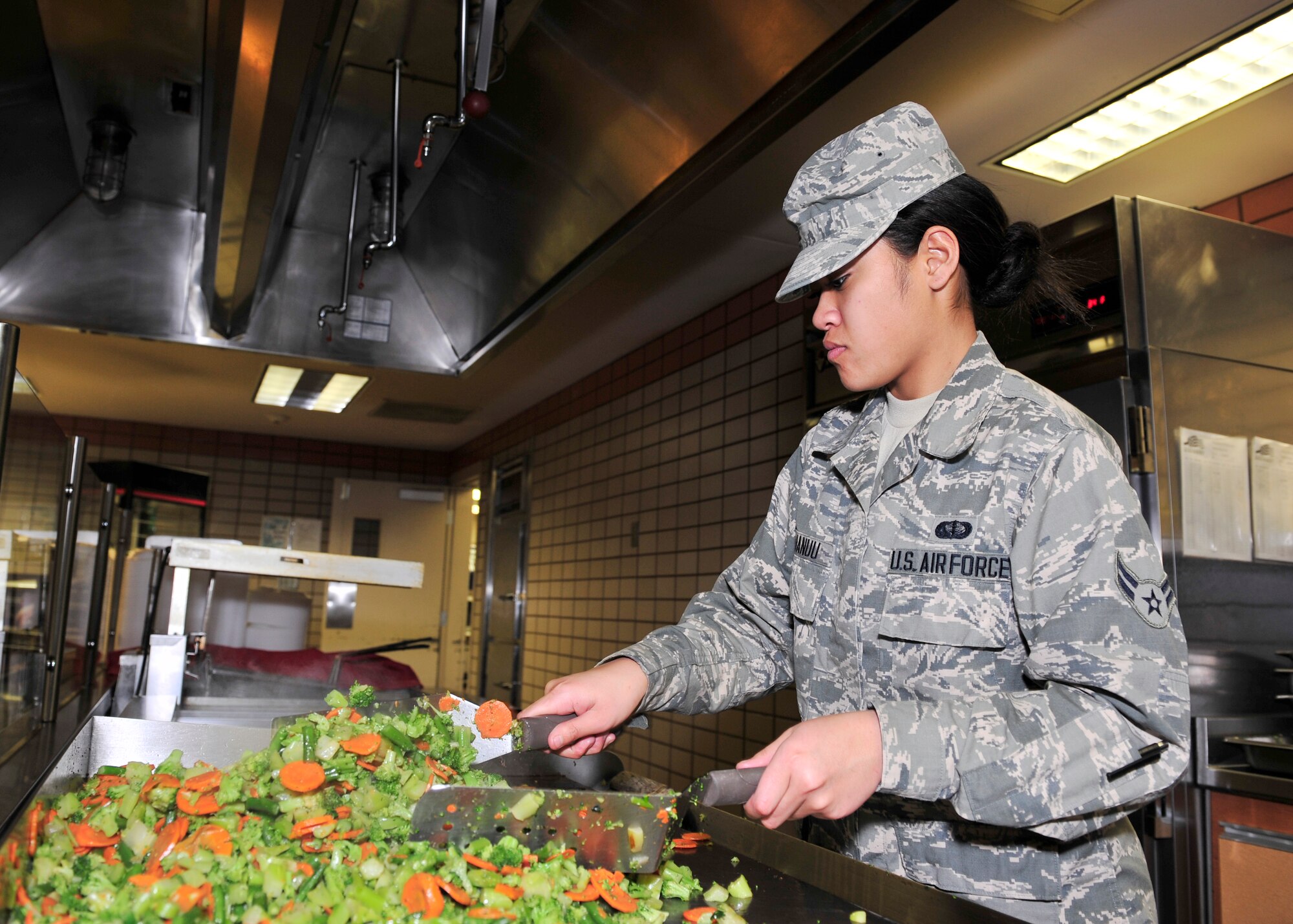 Airman 1st Class Leilani Taunauu, 354th Force Support Squadron food services apprentice, makes stir-fried vegetables Dec. 11, 2013, Eielson Air Force Base, Alaska. Vegetables were prepared for the Mongolian Barbecue meal hosted by the Two Seasons Dining Facility. (U.S. Air Force photo by Senior Airman Ashley Nicole Taylor/Released)