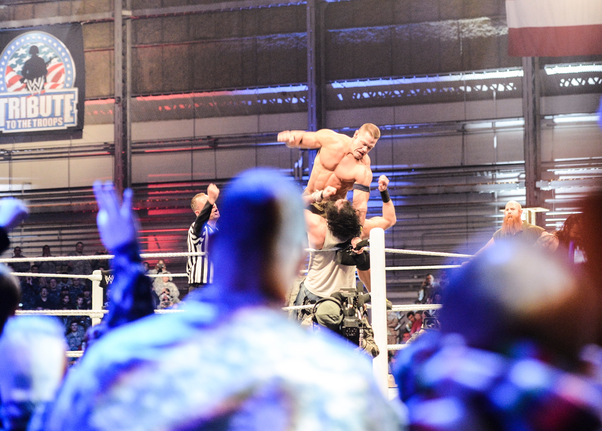 WWE superstar John Cena pounces on his opponent, Luke Harper, Dec. 13, 2013, during the WWE Tribute to the Troops event at Joint Base Lewis-McChord, Wash. Cena and Harper were among 40 WWE entertainers who visited JBLM to entertain service members and families. (U.S. Air Force photo/Tech. Sgt. Sean Tobin.)