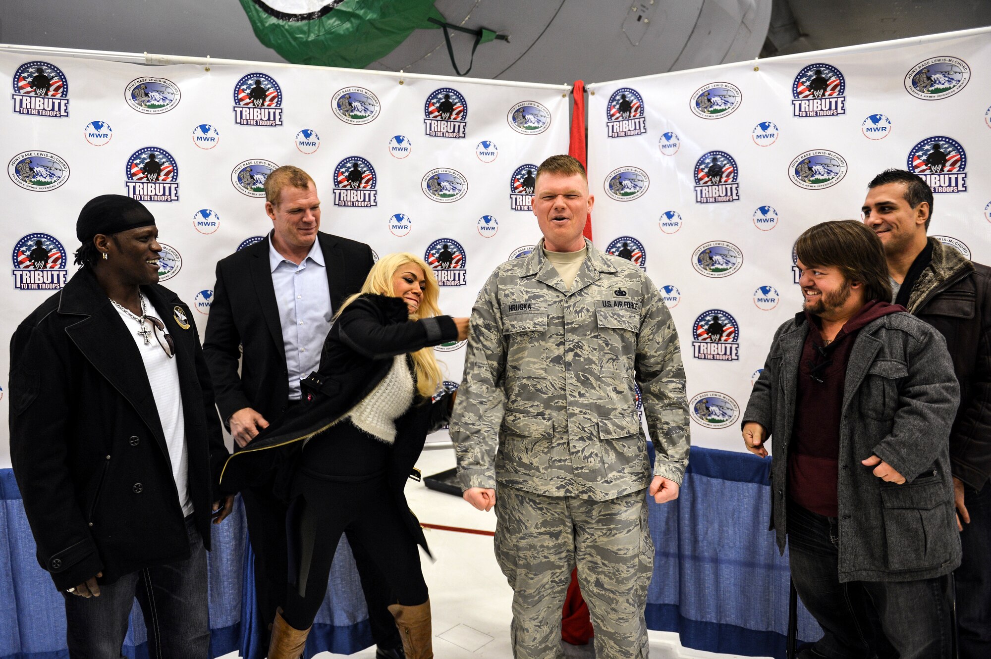 World Wrestling Entertainment Diva, Rosa Mendes, tacks on a stripe to the recently promoted Tech. Sgt. John Hruska, 627th Logistics Readiness Squadron central storage NCO in charge, Dec. 11, 2013 at Joint Base Lewis-McChord, Wash. Mendes, along with other WWE entertainers, toured McChord Field signing autographs as part of their Tribute to the Troops visit to JBLM. (U.S. Air Force photo/Staff Sgt. Jason Truskowski)