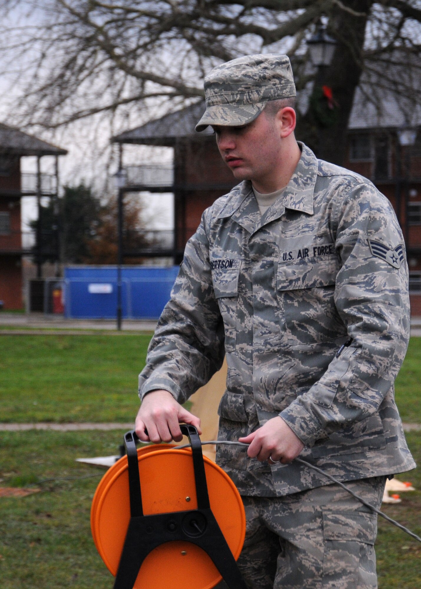 U.S. Air Force Senior Airman Calvin Robertson, 100th Communication Squadron Radio Frequency Transmission technician from San Antonio, lays audio cable for the 100th Air Refueling Wing Tree Lighting Ceremony Dec. 6, 2013, on RAF Mildenhall, England. The radio frequency transmissions shop personnel helped set up the public address system that was used for the Christmas tree lighting ceremony.The work center also provides tactical radio support to the 100th ARW and its tenant units. (U.S. Air Force photo by Gina Randall/Released)