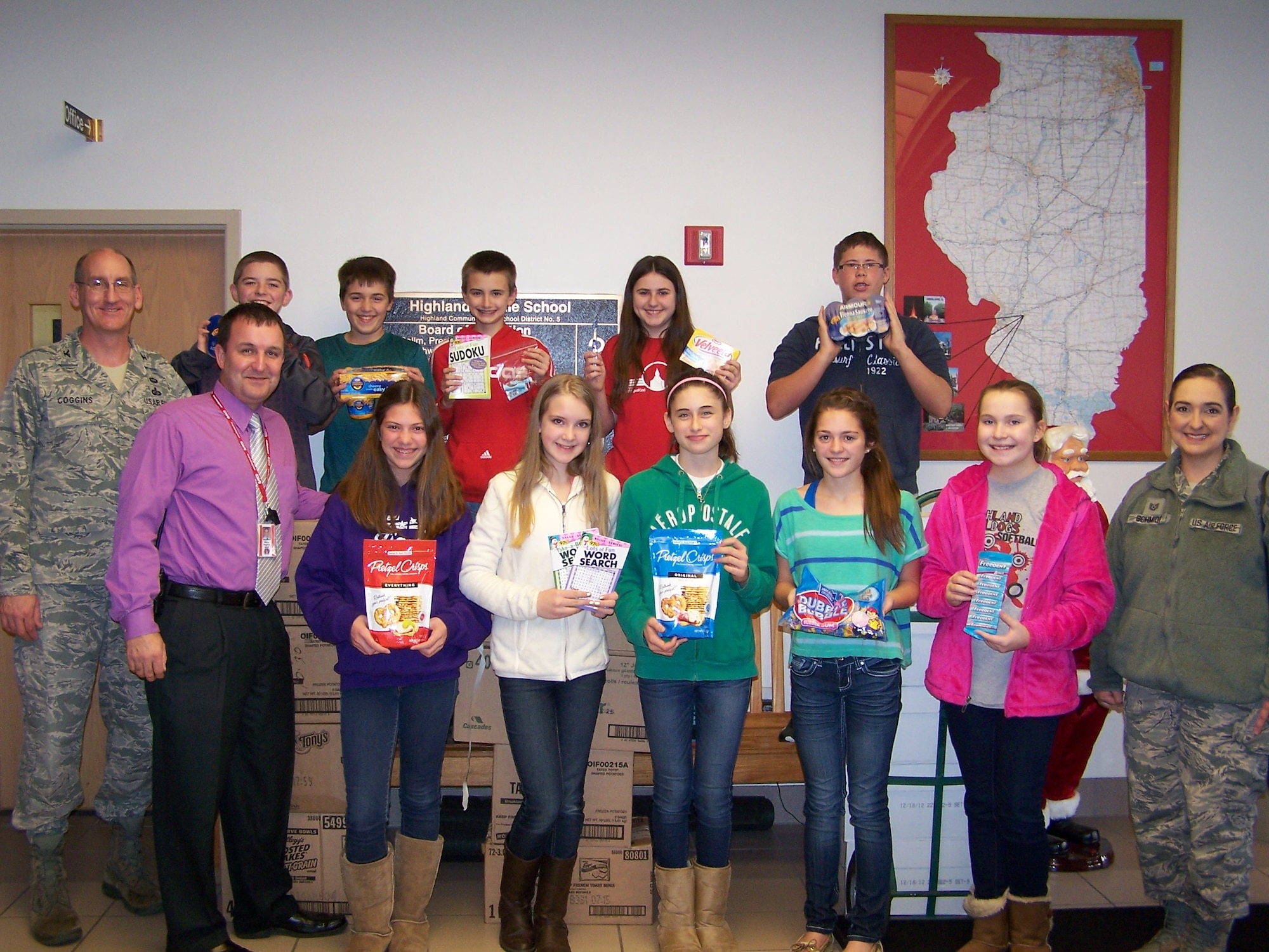 Col. George Coggins, Air Mobility Command Financial Management director, and Tech. Sgt. Sandra Schmidt, AMC/FM warplanner, meet with Highland Middle School students to thank and collect 30 care packages for deployed Airmen Dec. 4, 2013, in Highland, Ill. This is the eighth year in a row HMS has done this. (Courtesy photo)