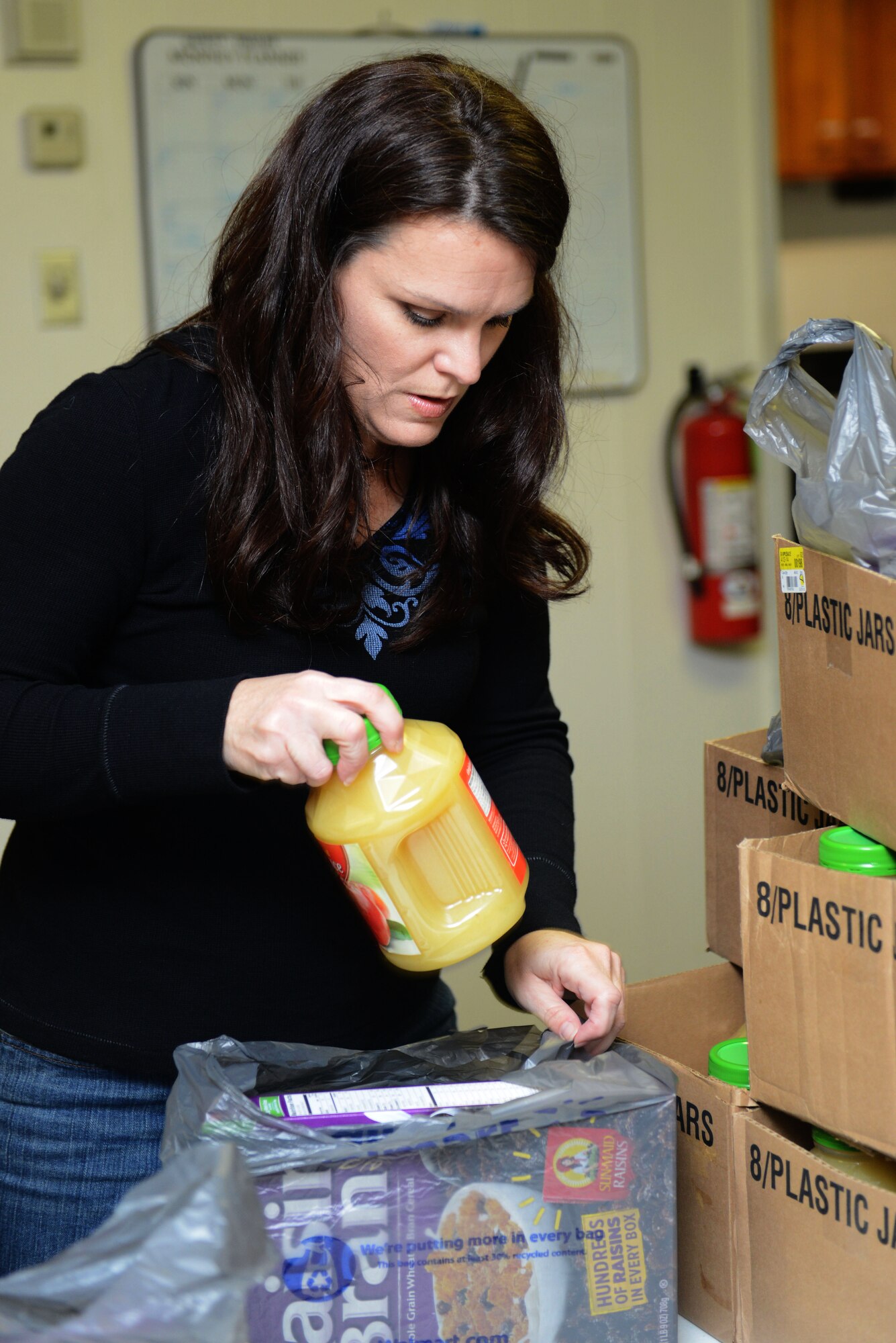 Teresa Laughlin, spouse of U.S. Air Force Maj. Clayton Laughlin, places a food item in a bag during the Air Land Sea Application Center’s community volunteer project with the Peninsula Agency on Aging program in Newport News, Va., Dec. 10, 2013. The program helped feed more than 370 home-bound elderly in the local community. (U.S. Air Force photo by Airman 1st Class Kimberly Nagle/Released)