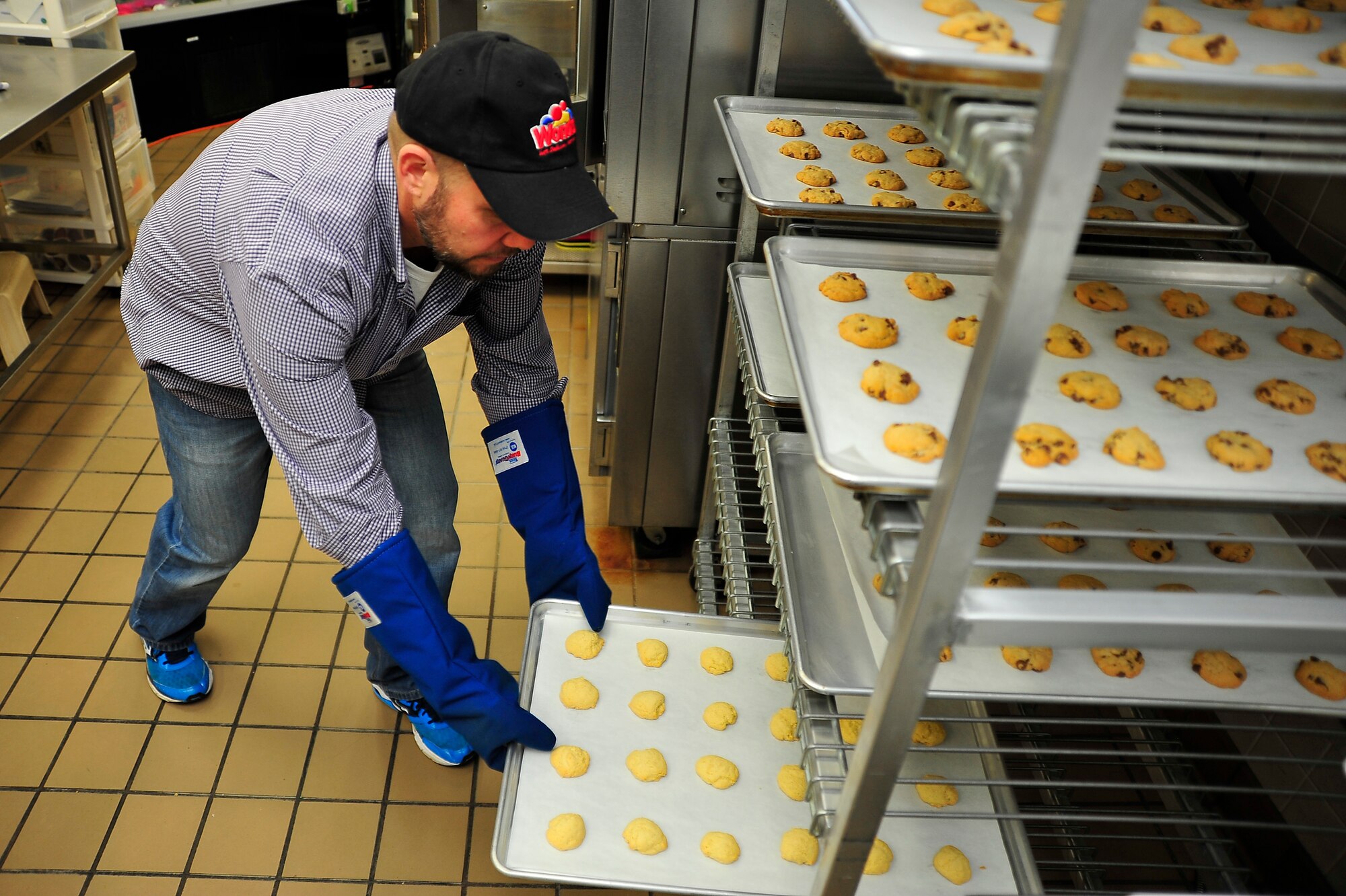 Matthew Whittaker, Defense Commissary Agency commissary store director, puts cookies on a cooling rack during the base’s annual Cookie Caper at Misawa Air Base, Japan, Dec. 9, 2013. The commissary made an agreement with cookie caper volunteers that if they came with their cookie dough prepared, the commissary would provide the workspace, tables, baking sheets and oven. (U.S. Air Force photo by Staff Sgt. Nathan Lipscomb) 