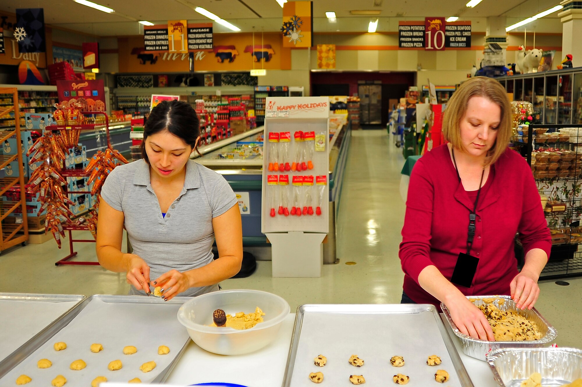 (From left to right) Kelley Zuniga and Lisa Hook make cookies at the Misawa Commissary during the Cookie Caper at Misawa Air Base, Japan, Dec. 9, 2013. This is the second year the Commissary has opened its doors for cookie caper volunteers to use its high capacity oven. (U.S. Air Force photo by Staff Sgt. Nathan Lipscomb) 