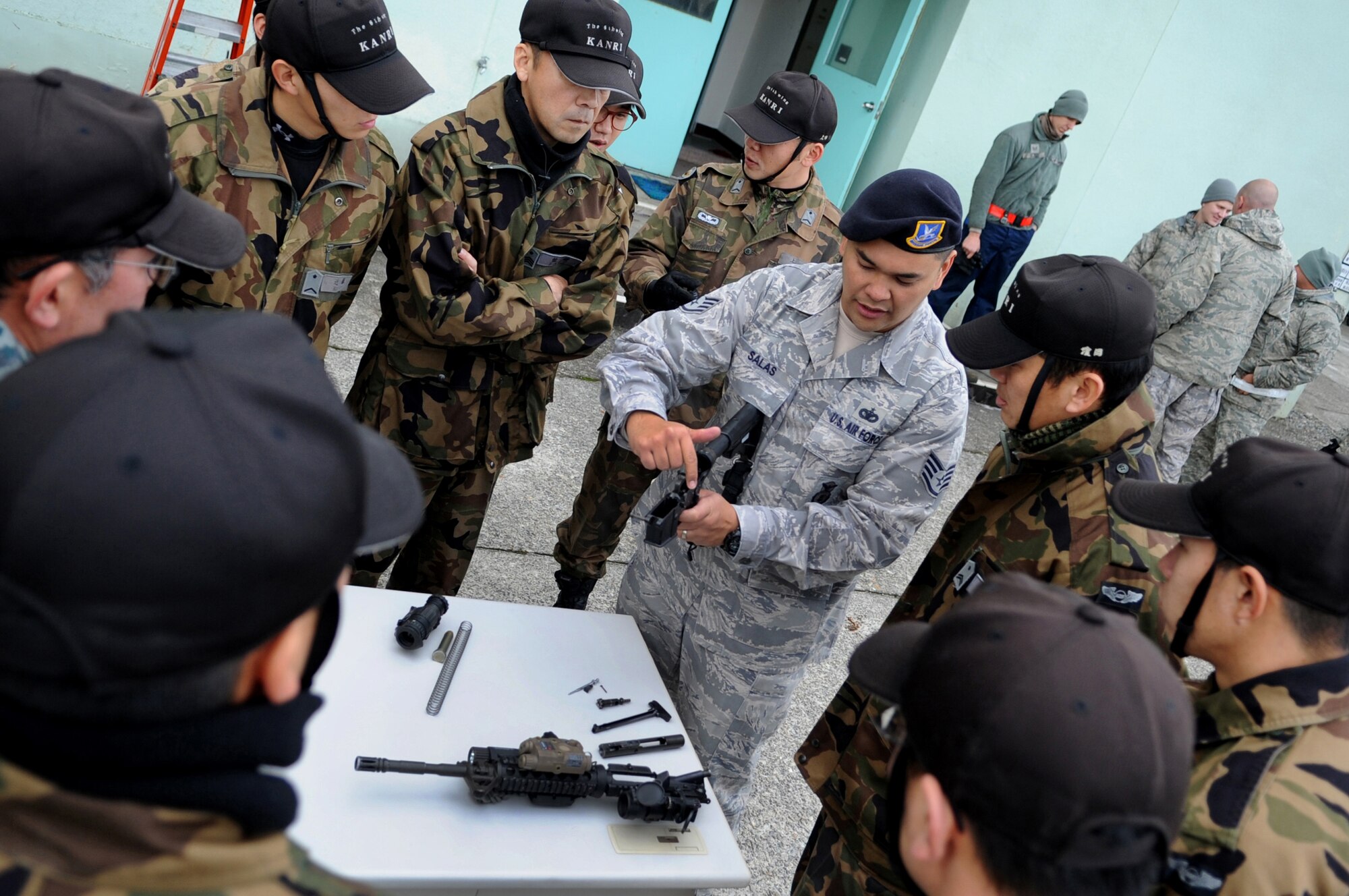U.S. Air Force Staff Sgt. Francisco Salas, 18th Security Forces Squadron armory NCO in charge, show members from the Japanese Air Self Defense Force 6th Wing Security Guard Squadron, pieces of an M-4 rifle during a security forces demonstration at Komatsu Air Base, Japan, Dec. 11, 2013. U.S and Japanese security members held an exchange to promote interoperability during an Aviation Training Relocation Program. During the exchange Salas showed JASDF members how to disassemble and assemble an M-4 rifle. (U.S. Air Force photo by Staff Sgt. Amber E. N. Jacobs)