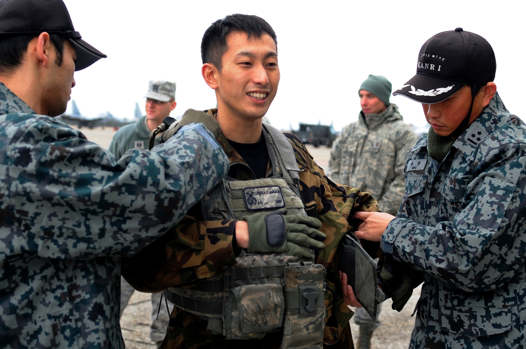 A security guard from Japanese Air Self Defense Force 6th Wing tries on a U.S. Air Force security forces flak vest during a demonstration at Komatsu Air Base, Japan, Dec. 11, 2013. U.S and Japanese security members held an exchange to promote interoperability during an Aviation Training Relocation Program. (U.S. Air Force photo by Staff Sgt. Amber E. N. Jacobs)